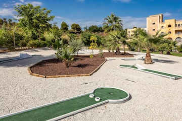 a mini golf course with palm trees and a building in the background