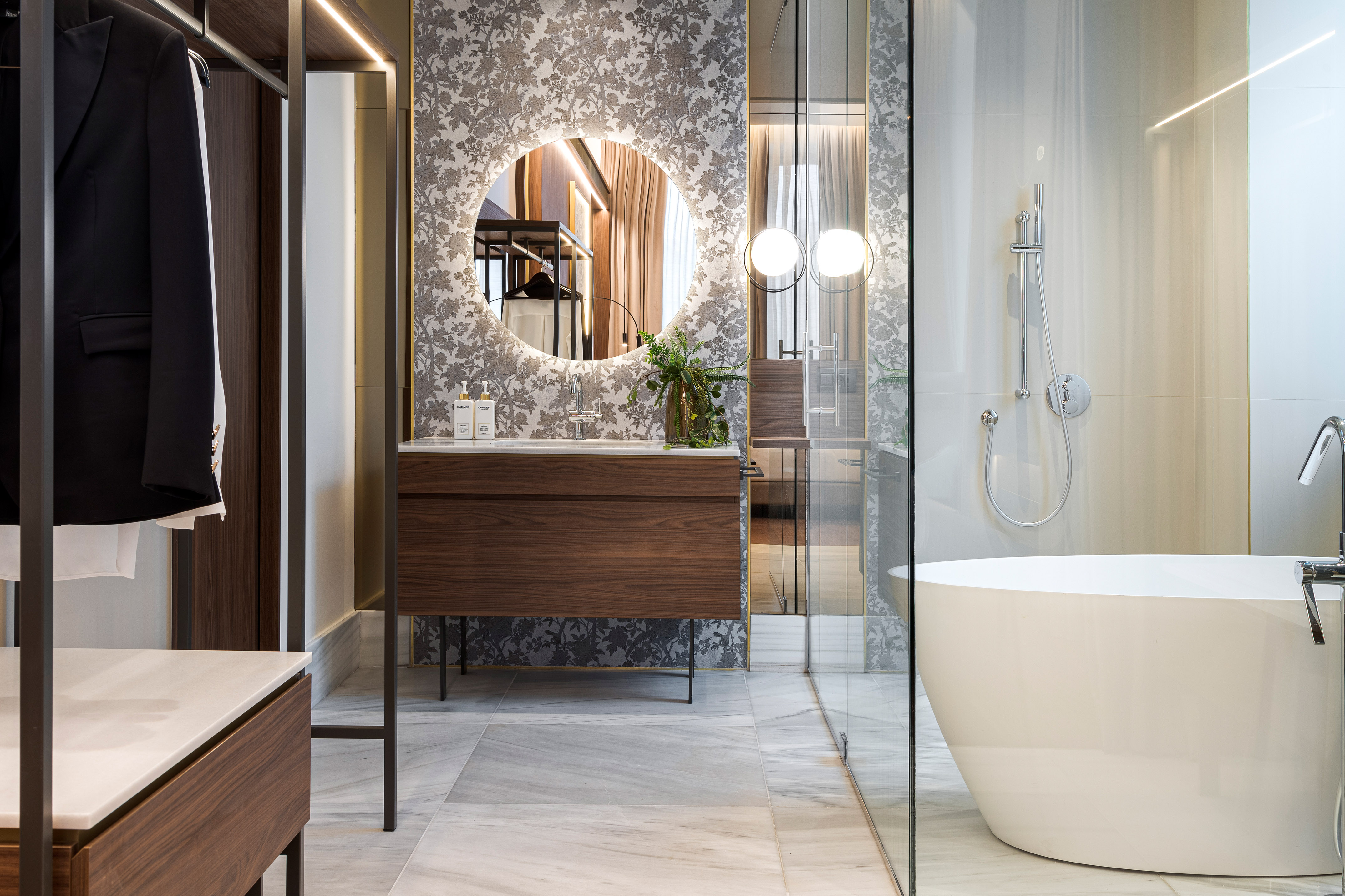 Luxury bathroom with wood vanity, backlit mirror, freestanding tub, and closet.