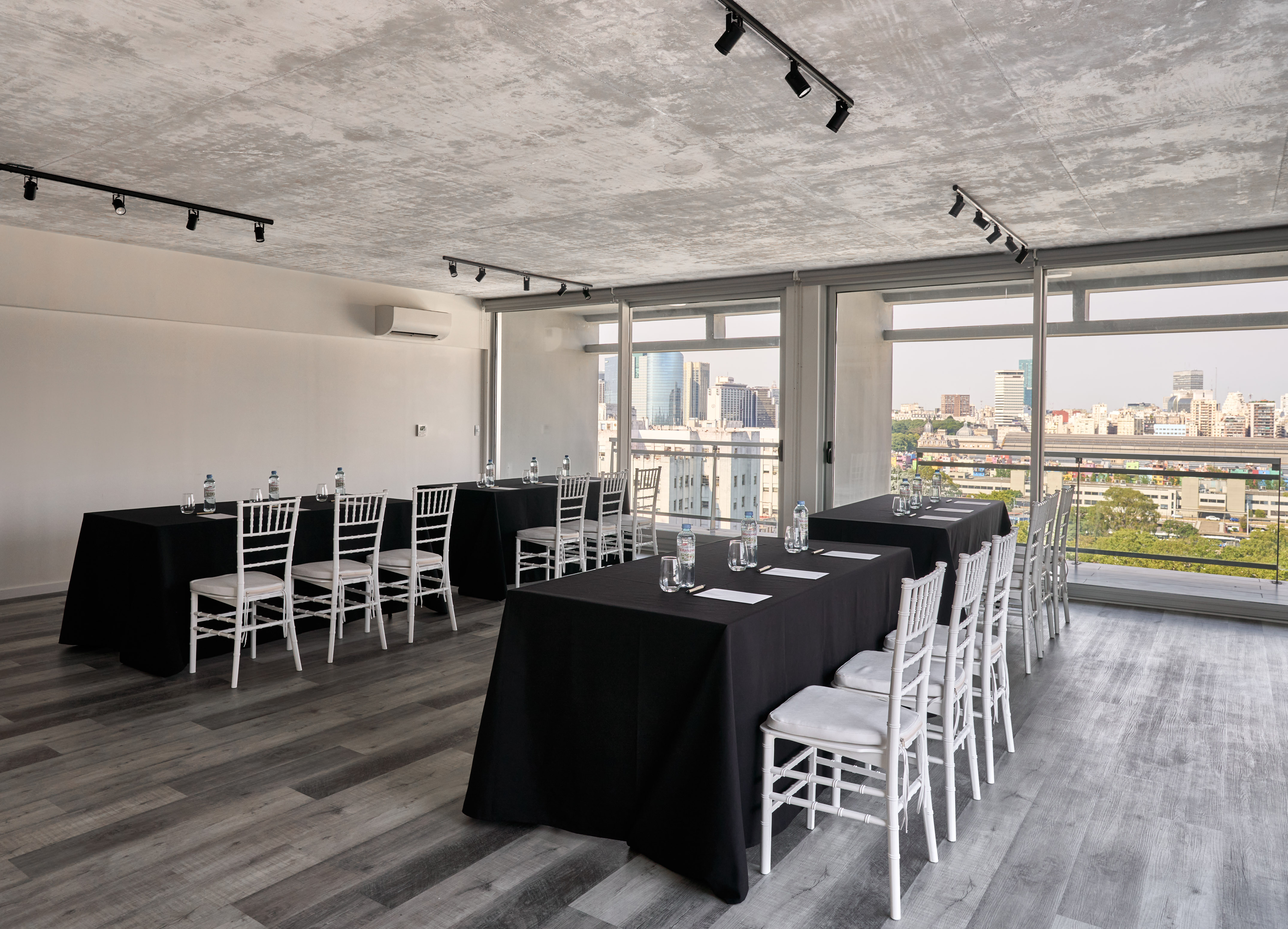 Modern conference room with city view, black tables, and white chairs.