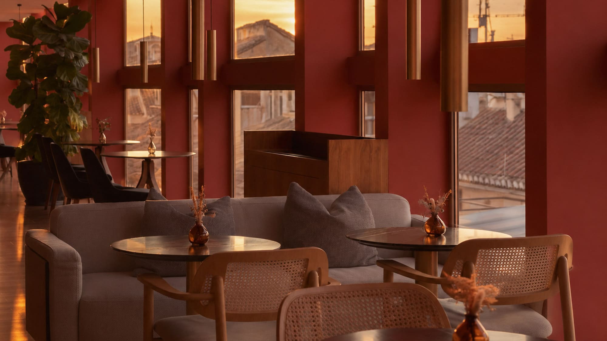Red-walled lounge interior with sunset city view, modern seating, and pendant lights.