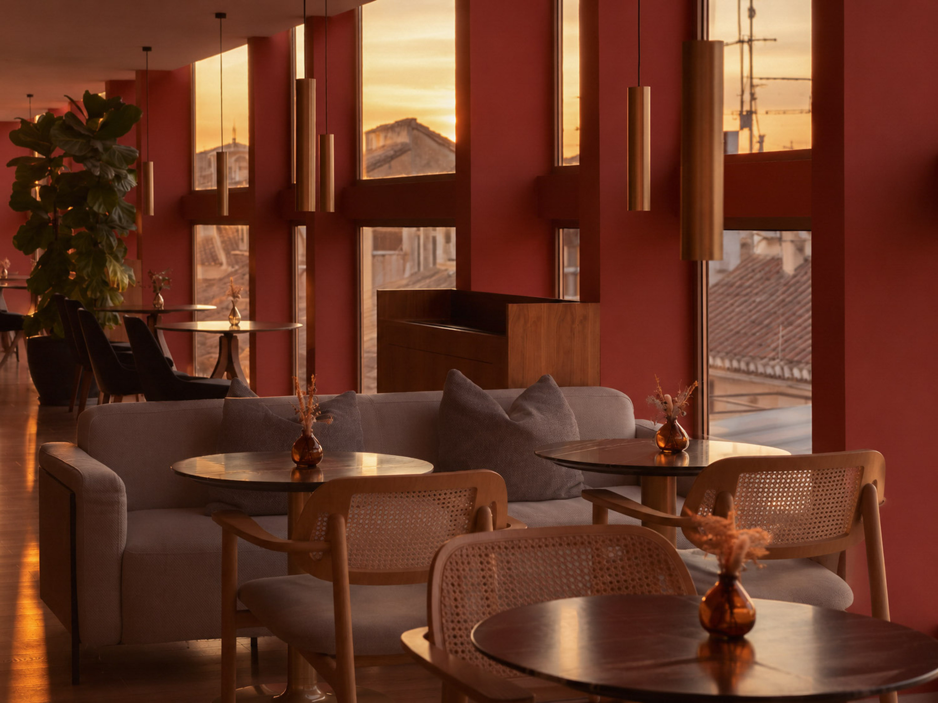 Red-walled lounge interior with sunset city view, modern seating, and pendant lights.