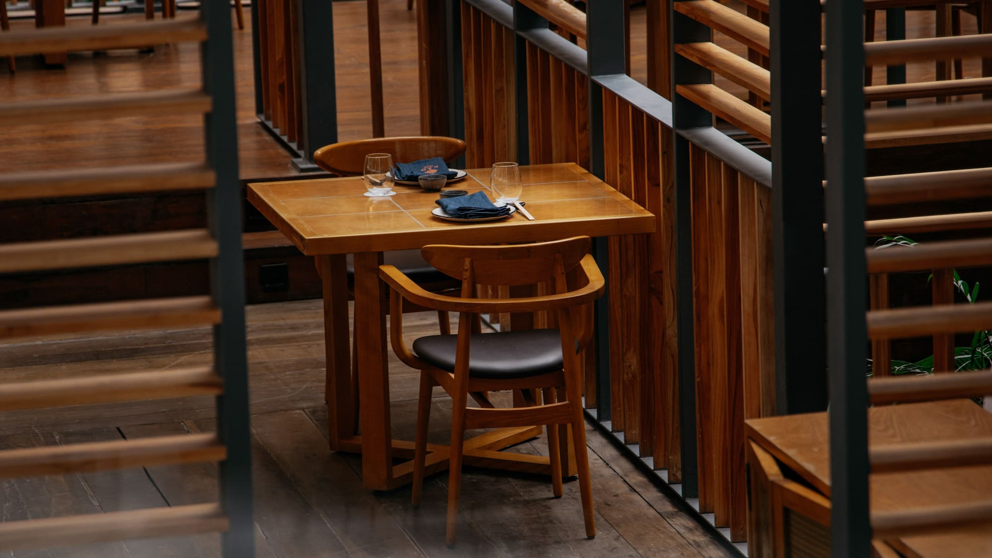 Wooden restaurant interior with dining tables, chairs, and slatted screens.