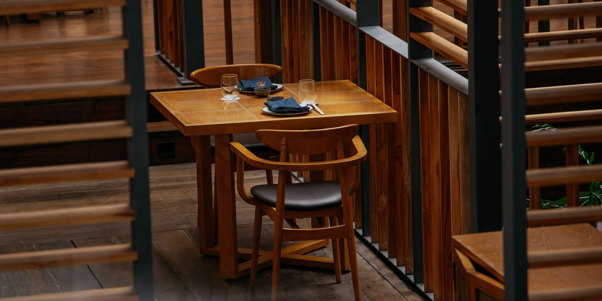 Wooden restaurant interior with dining tables, chairs, and slatted screens.