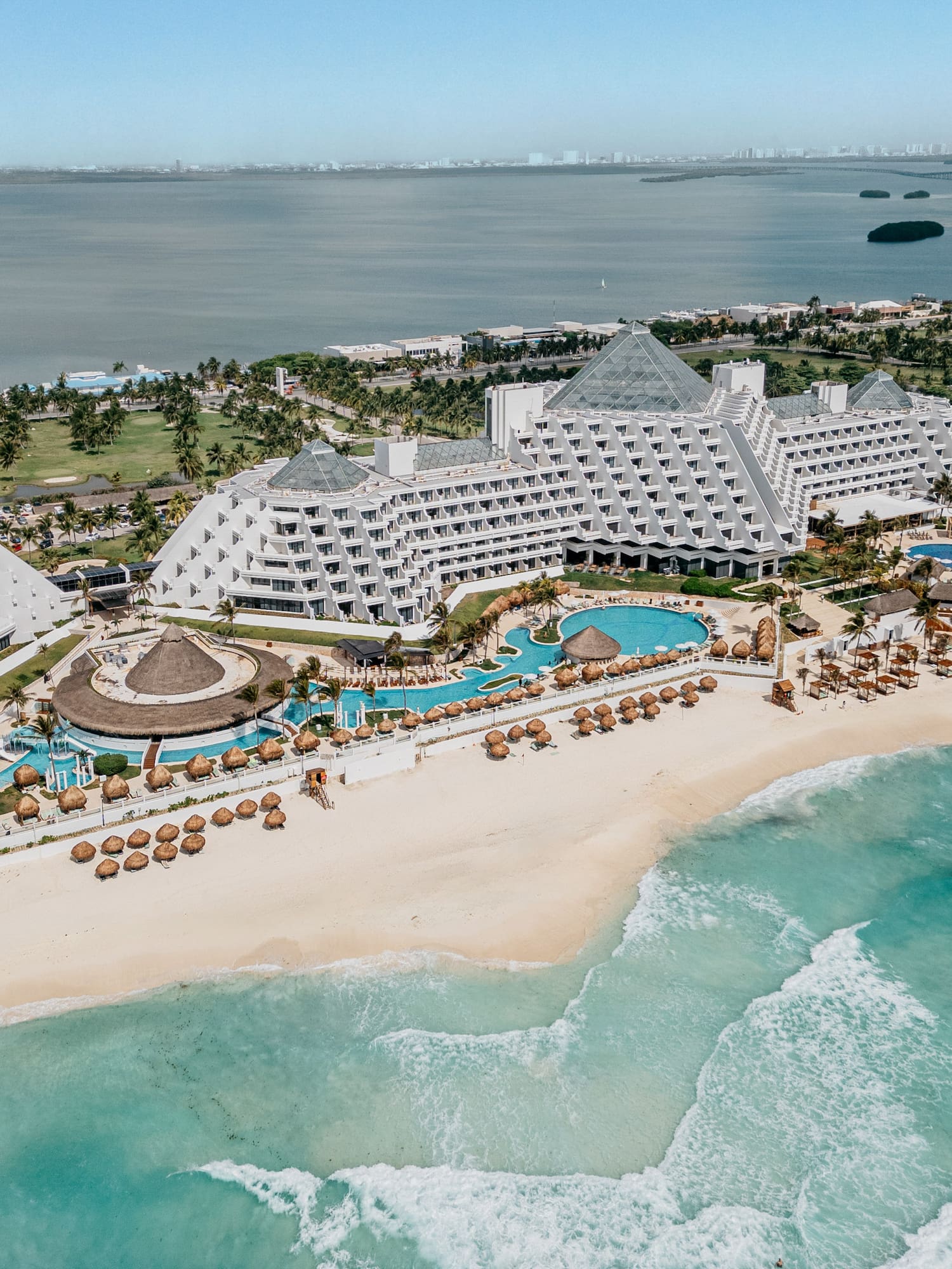 Cancun luxury beach resort aerial: pyramid hotels, pools, turquoise ocean.