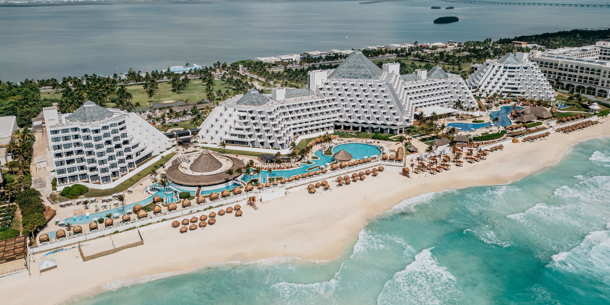 Cancun luxury resort on white sand beach, pyramid hotels, turquoise ocean.