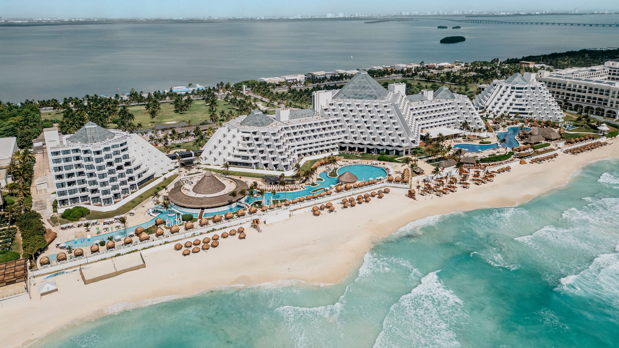 Aerial of Cancun pyramid resort on a white sand beach with turquoise ocean.