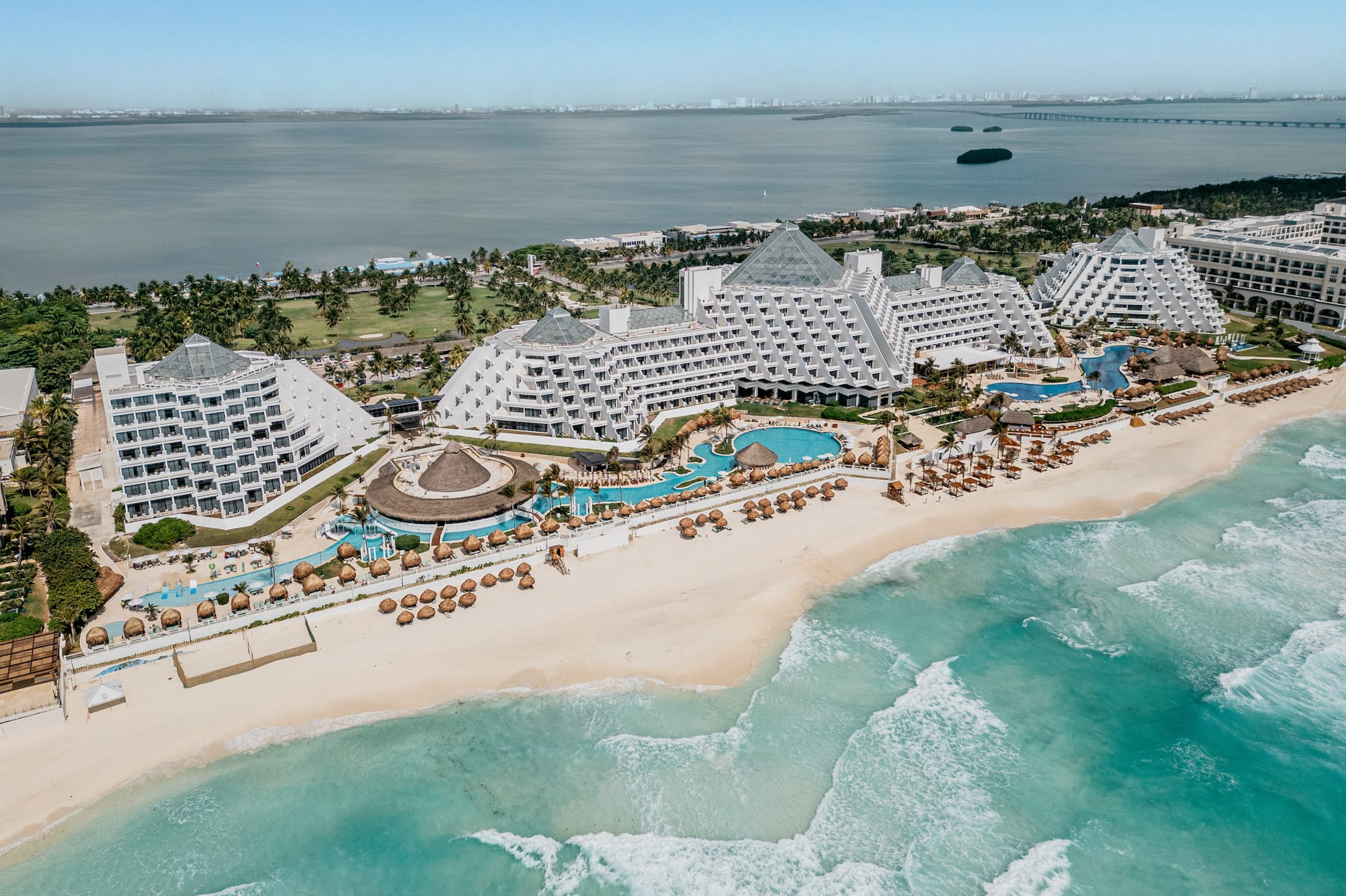 Aerial of Cancun pyramid resort on a white sand beach with turquoise ocean.