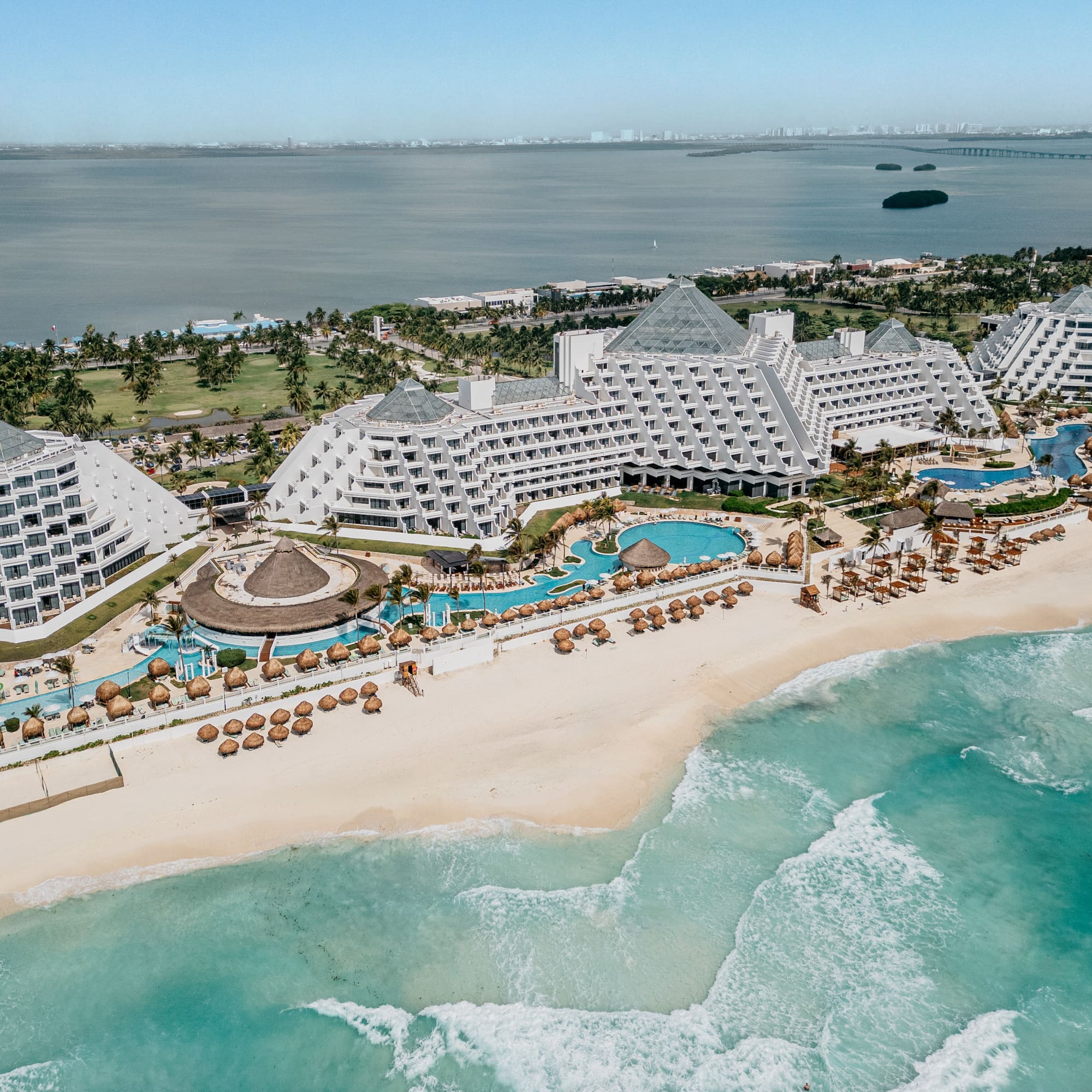 Cancun luxury resort: pyramid buildings, white beach, turquoise ocean, pools.