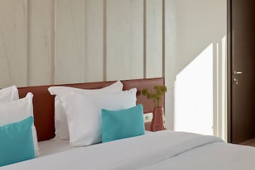 a bed with white sheets and blue pillow