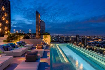 a rooftop pool with a large pool and a city skyline at night
