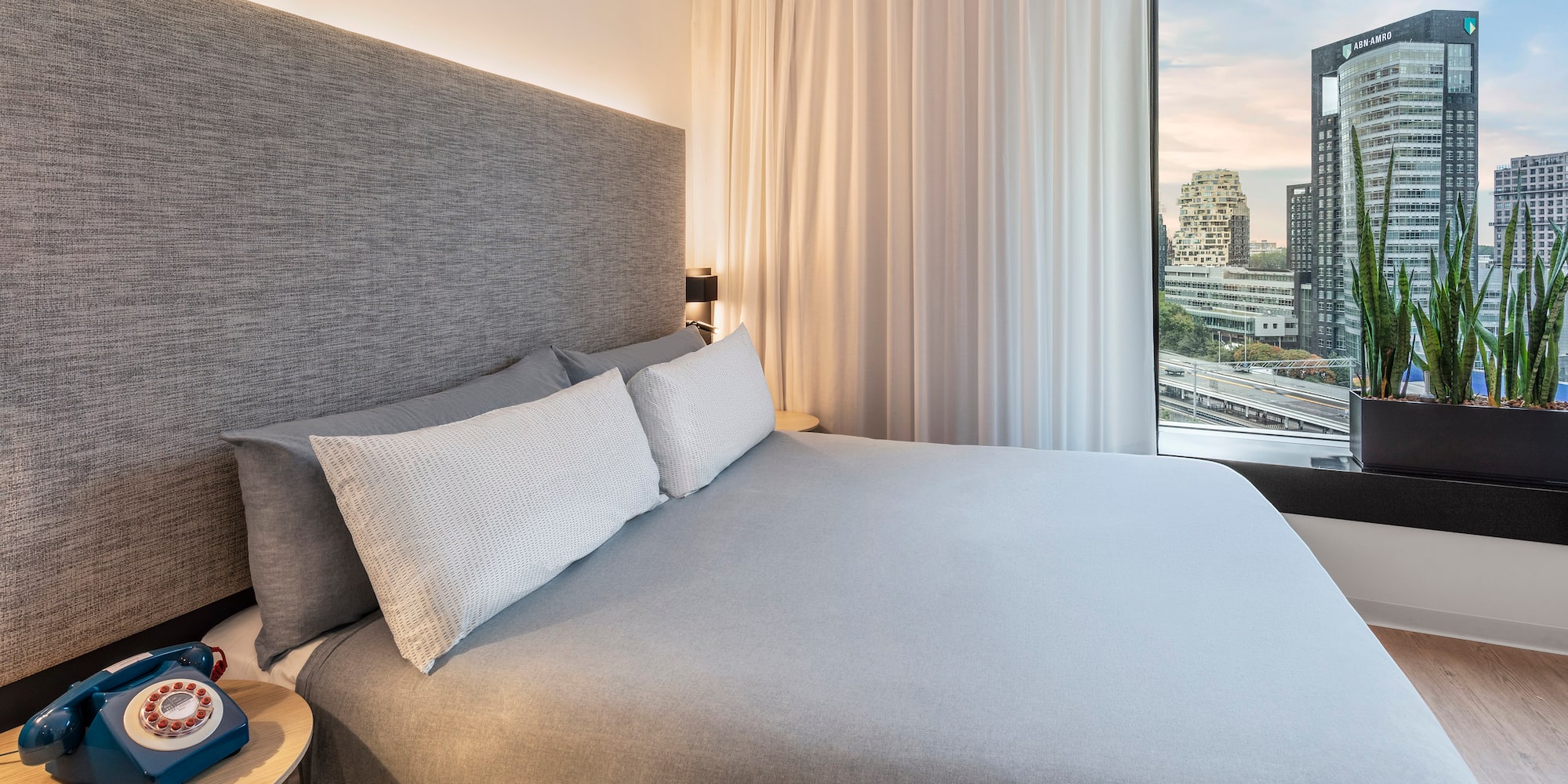 a bed with a large headboard and a table with a window