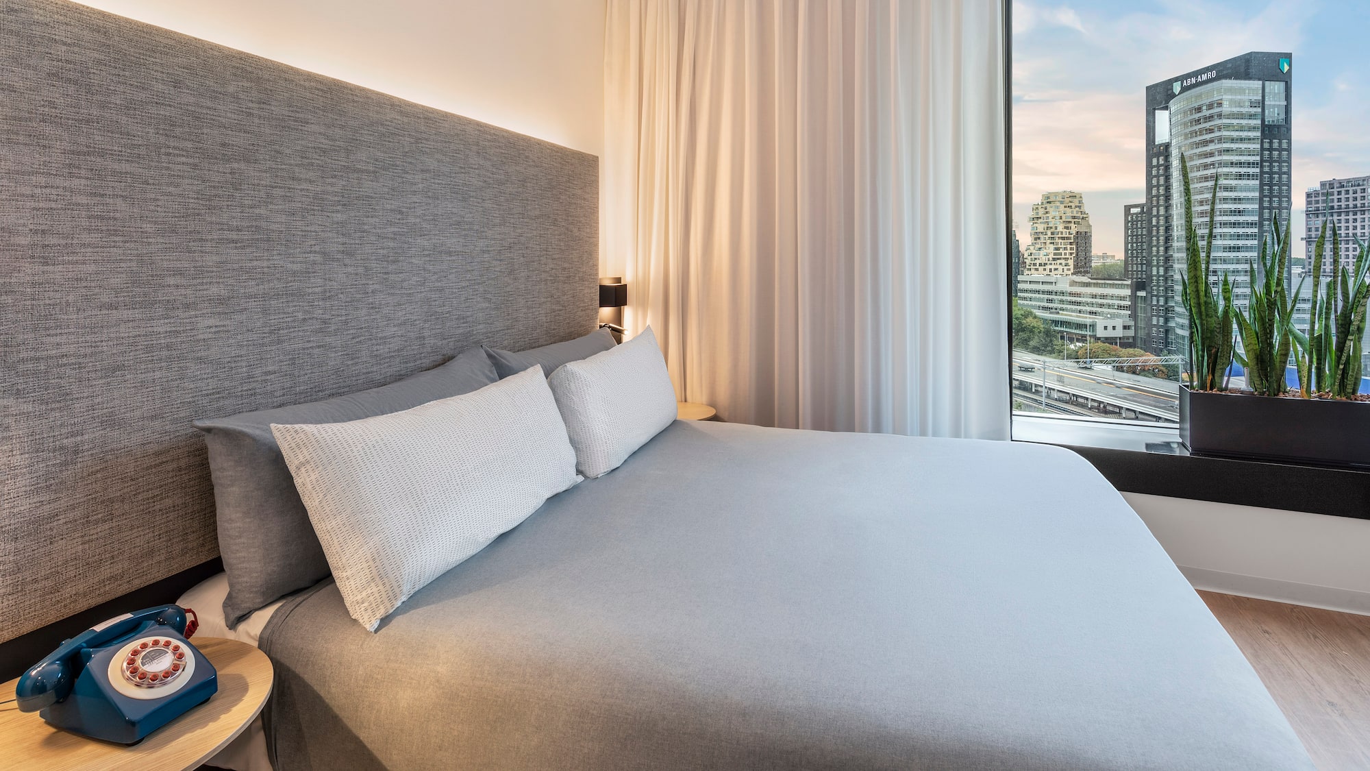 a bed with a large headboard and a table with a window