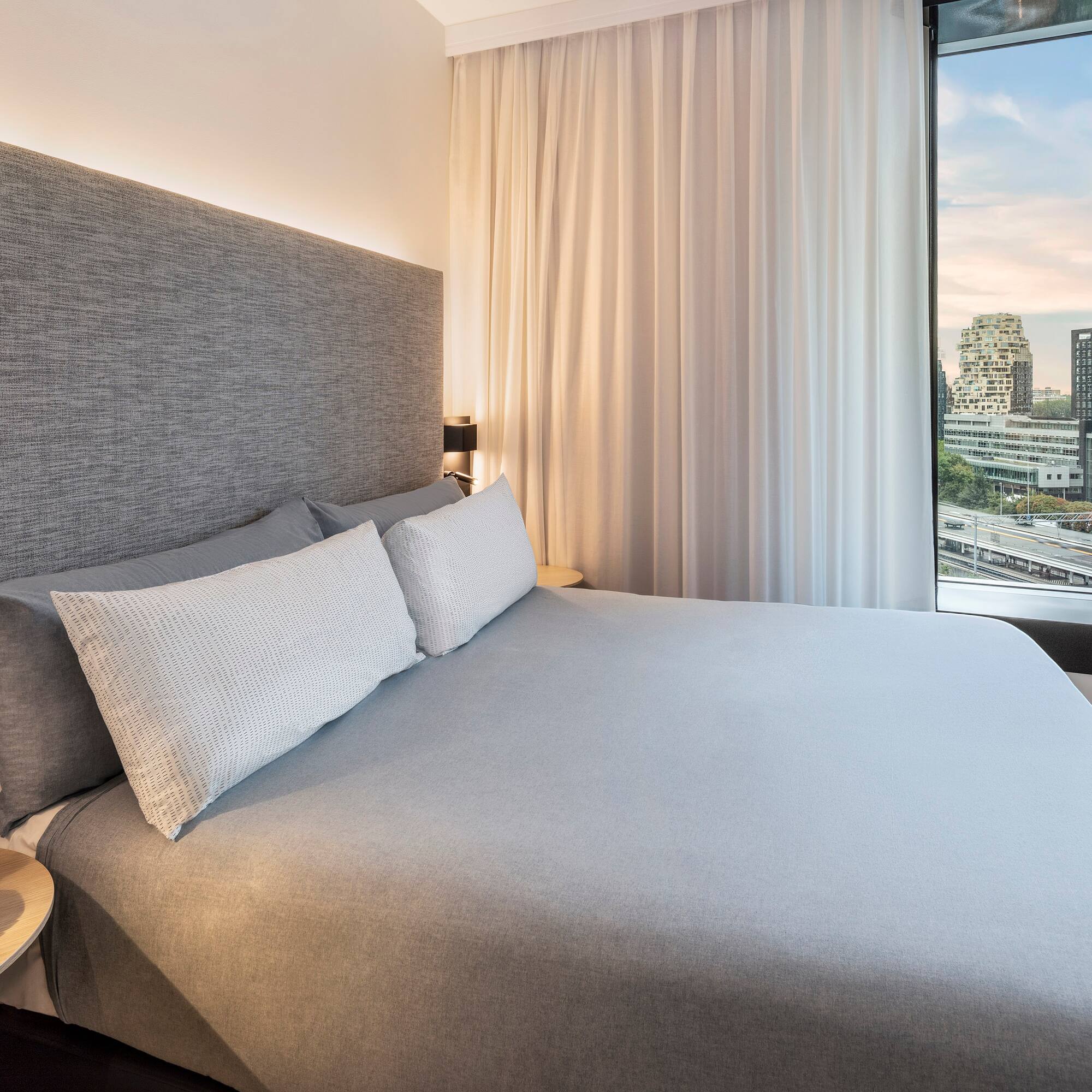 a bed with a large headboard and a table with a window