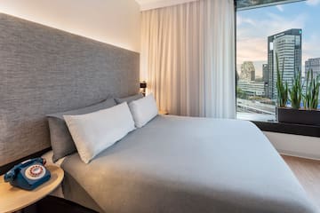 a bed with a large headboard and a table with a window