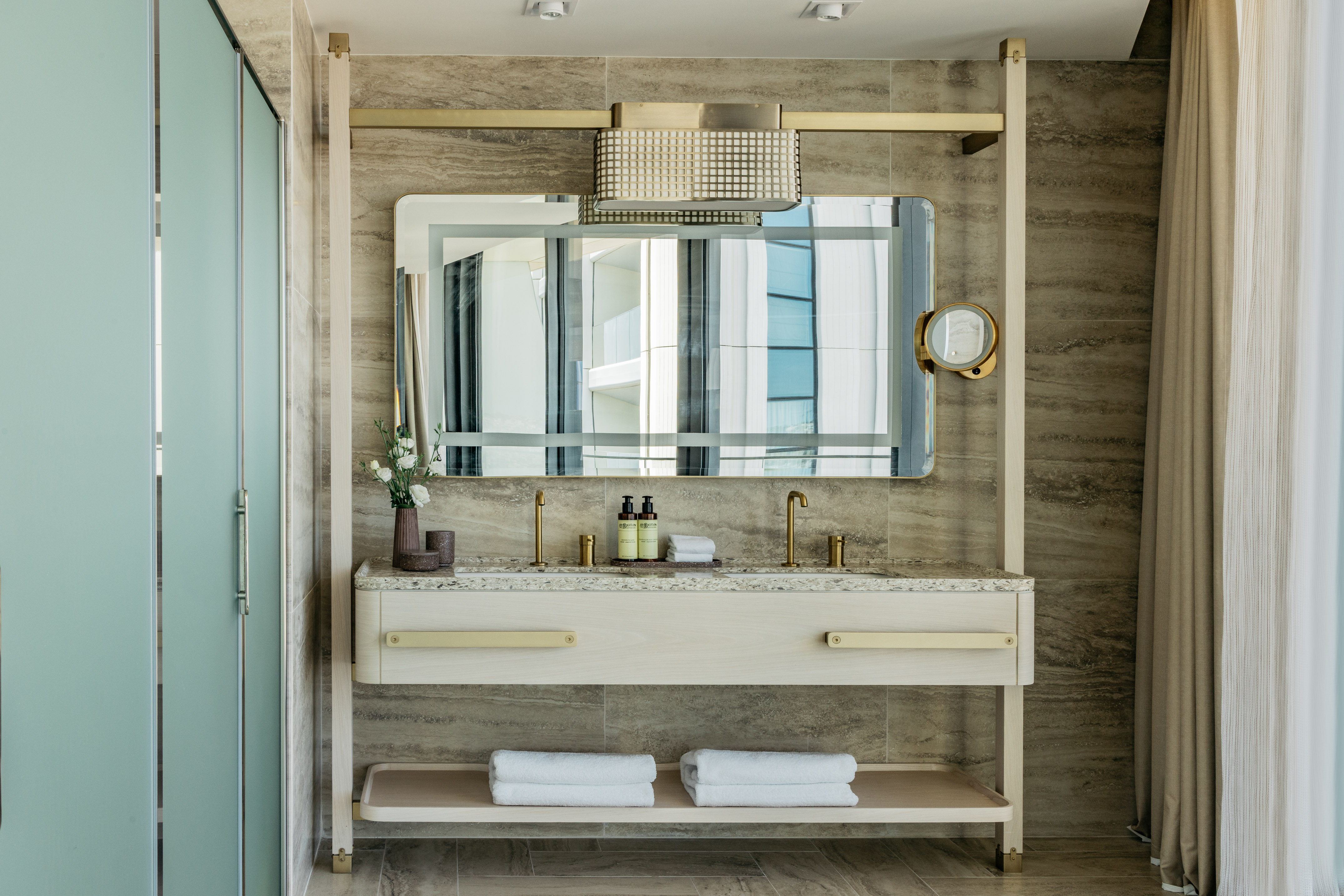 Modern bathroom vanity with double sinks, gold faucets, and white towels.
