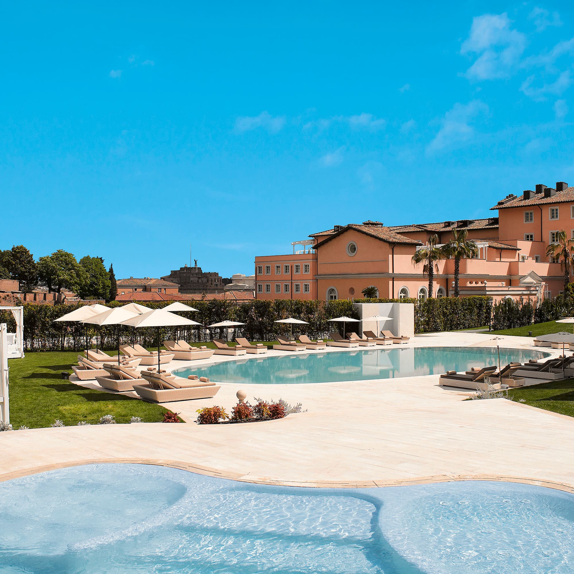 a pool with lounge chairs and umbrellas in front of a building