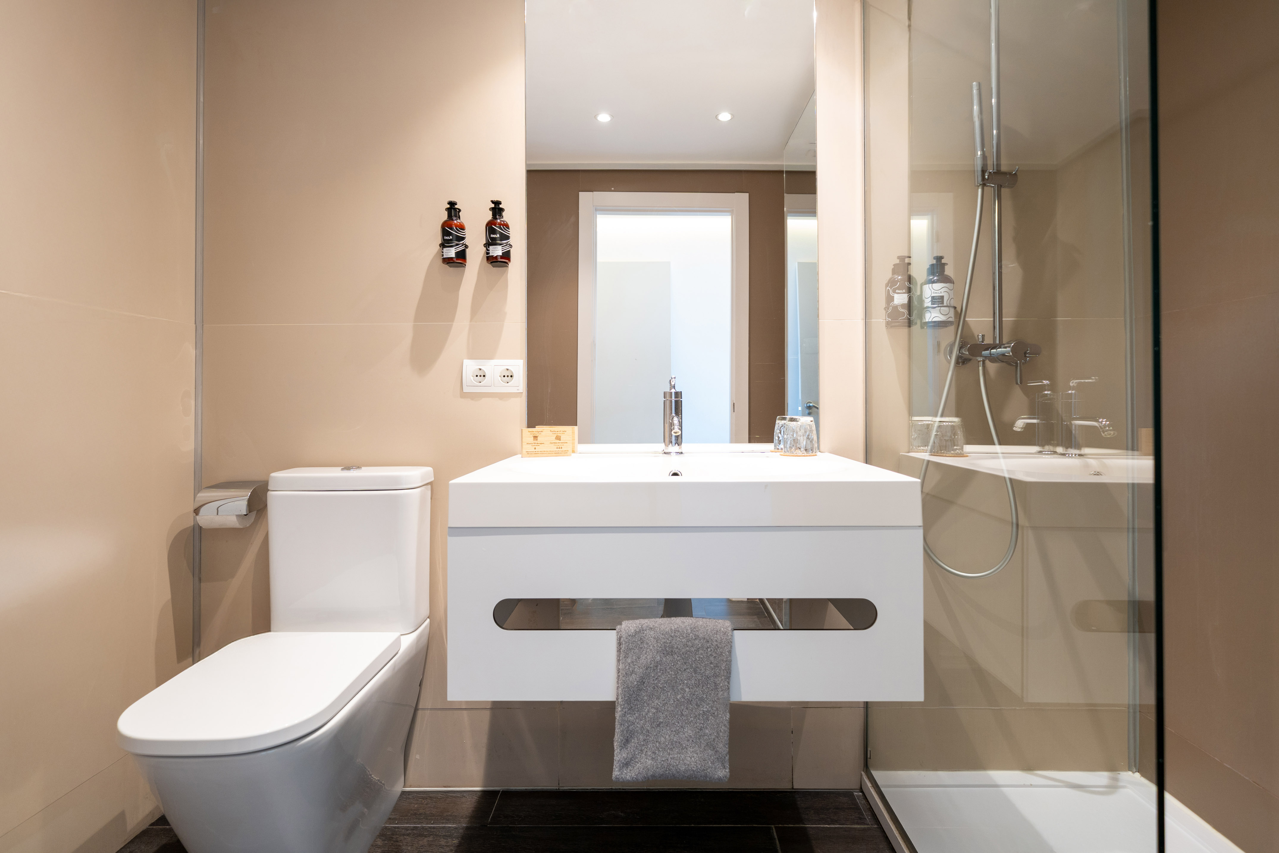 Modern bathroom with white toilet, floating vanity, mirror, and shower.
