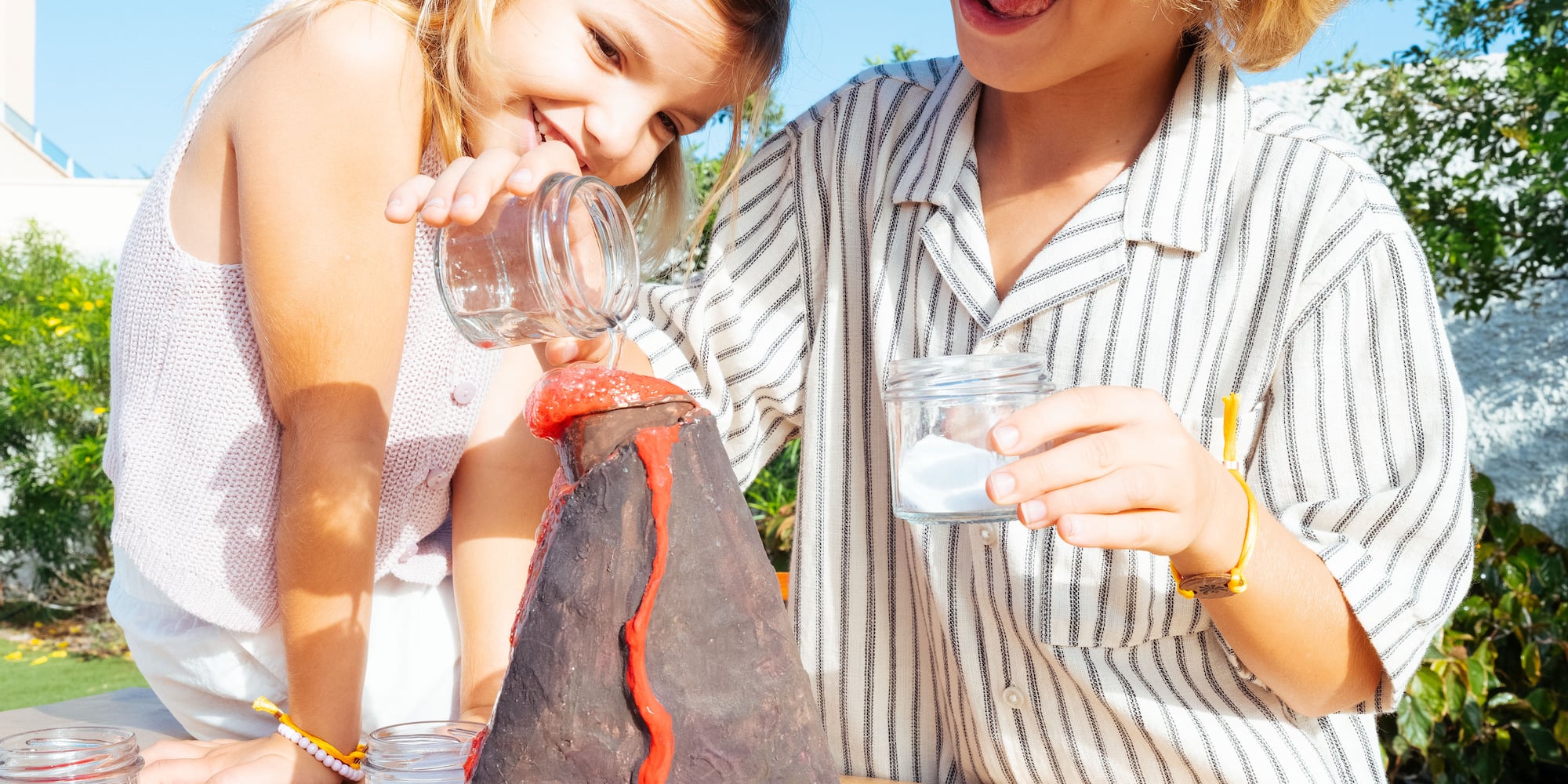 Kids outdoor STEM volcano experiment, red lava erupting and spilling.