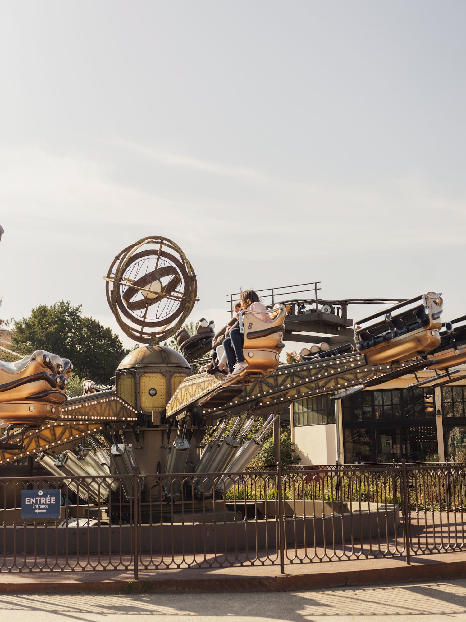 Guests on a gold-accented steampunk amusement park ride.