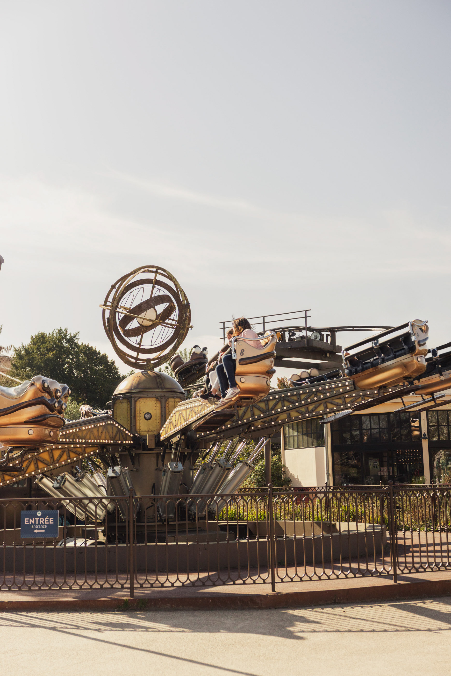 Guests on a gold-accented steampunk amusement park ride.