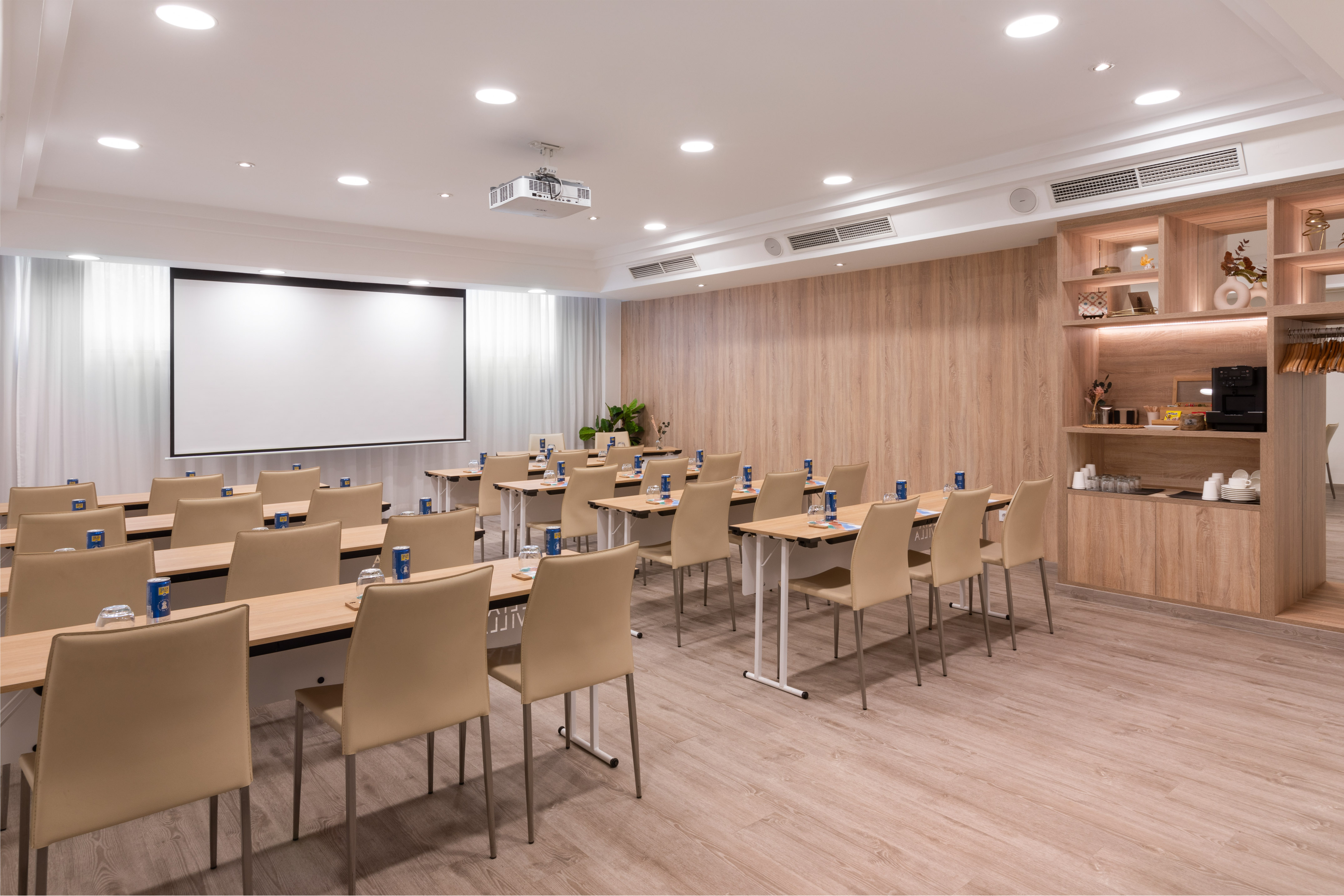 Modern conference room with screen, tables, chairs, and coffee station.
