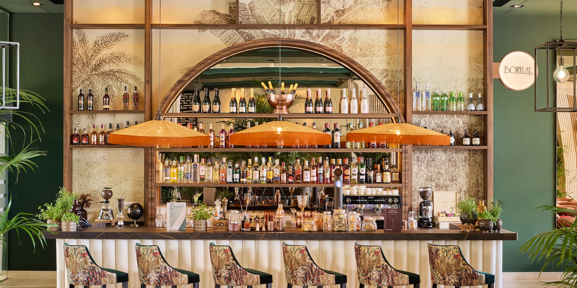 Stylish hotel bar with patterned stools, liquor bottles, and tropical decor.