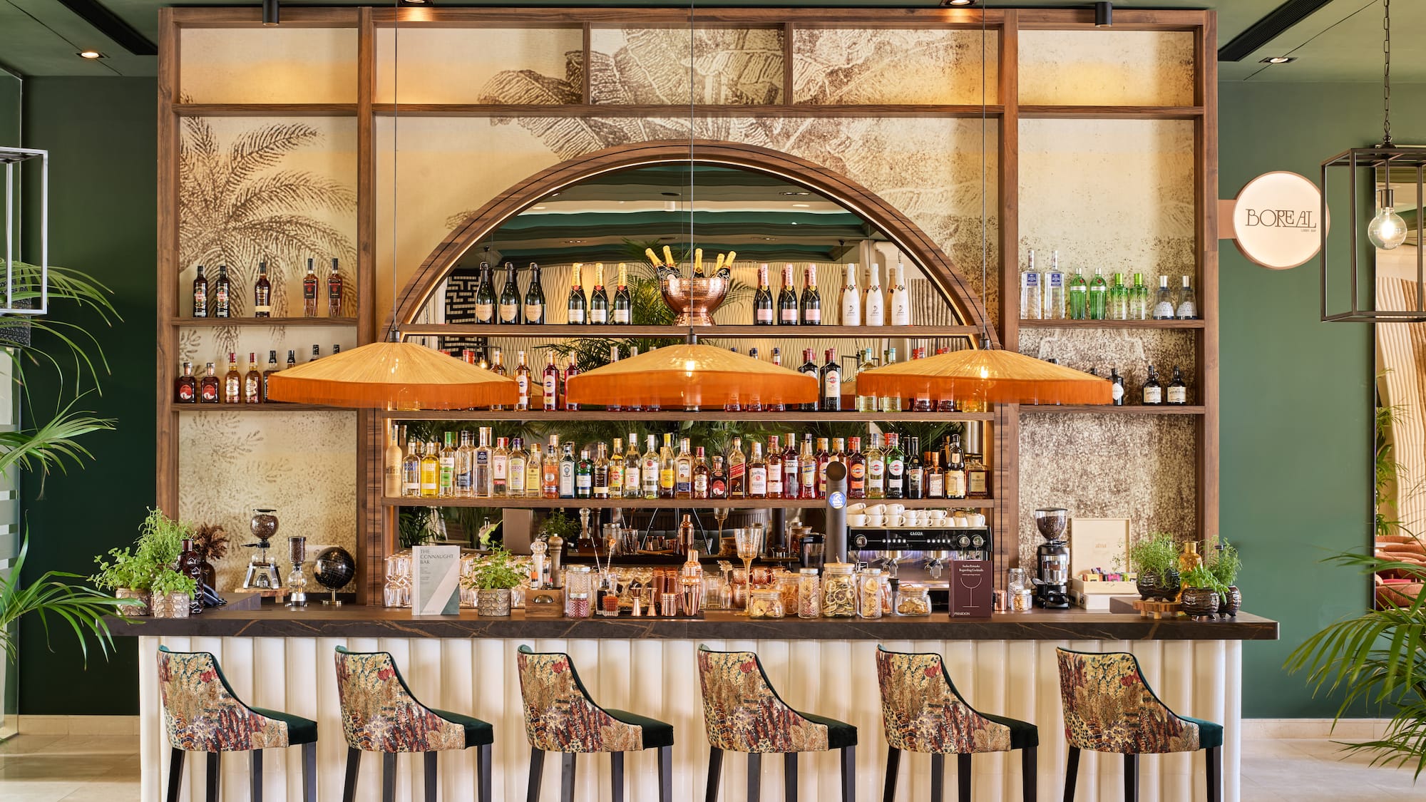 Elegant green hotel bar with wood liquor display and unique patterned stools.