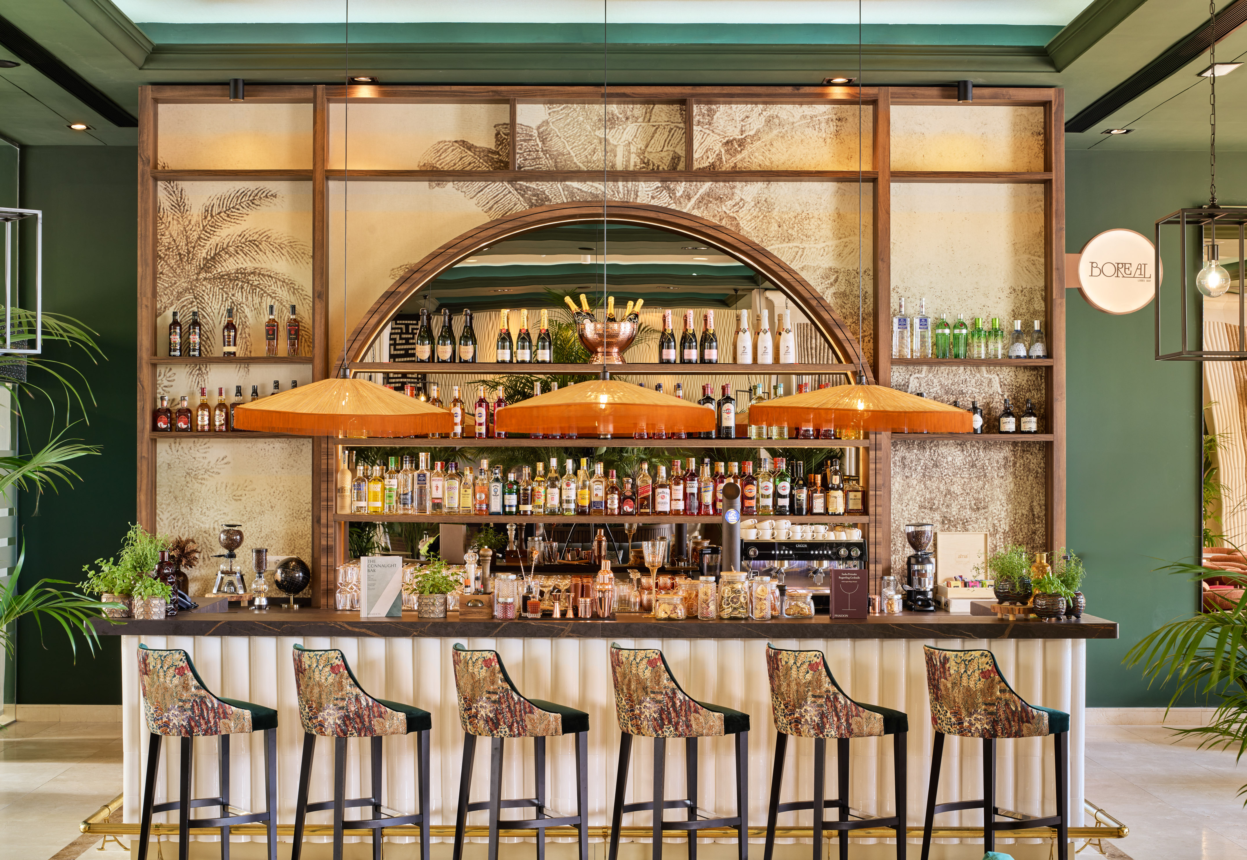 Stylish hotel bar with patterned stools, liquor bottles, and tropical decor.