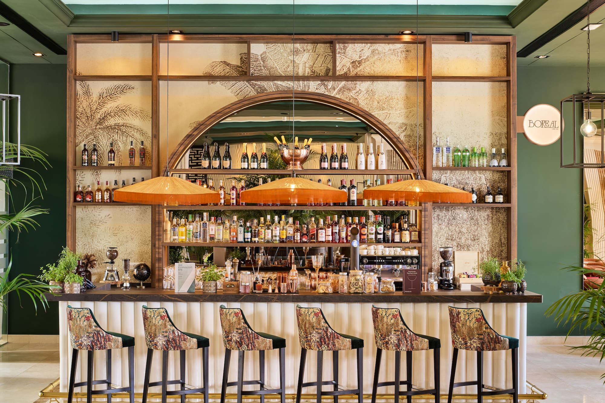 Stylish hotel bar with patterned stools, liquor bottles, and tropical decor.