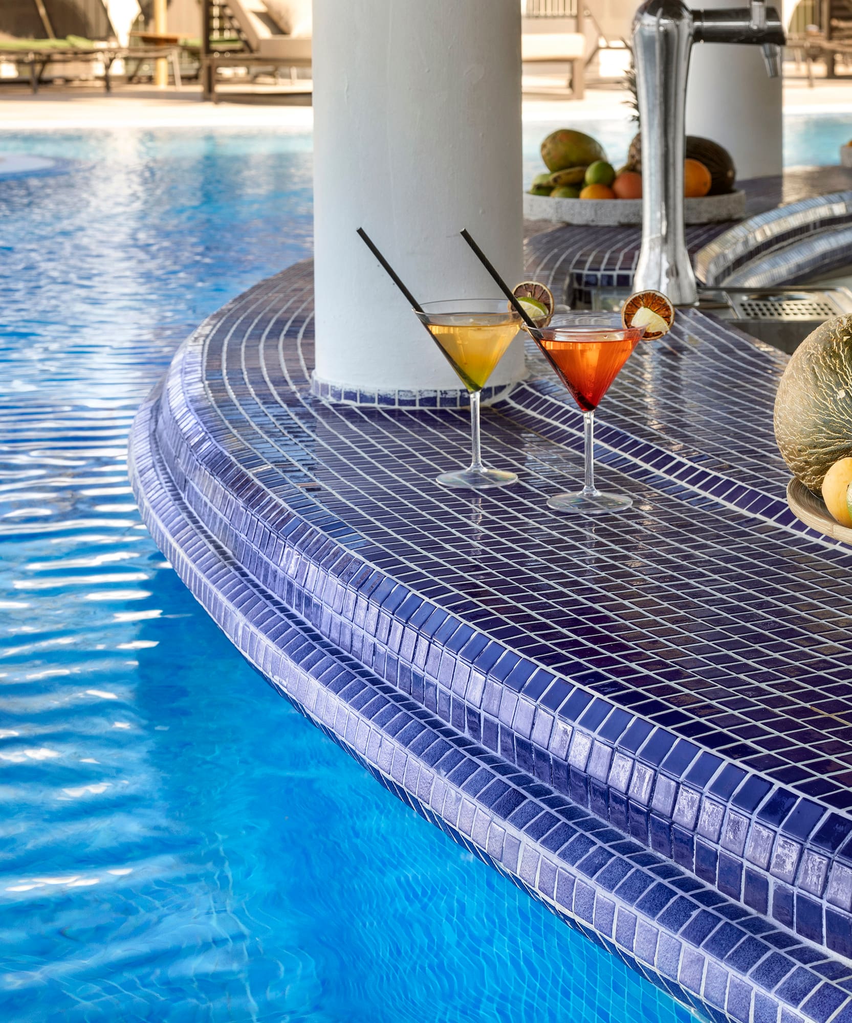 a pool with a bowl of fruit and a plate of fruit on the side