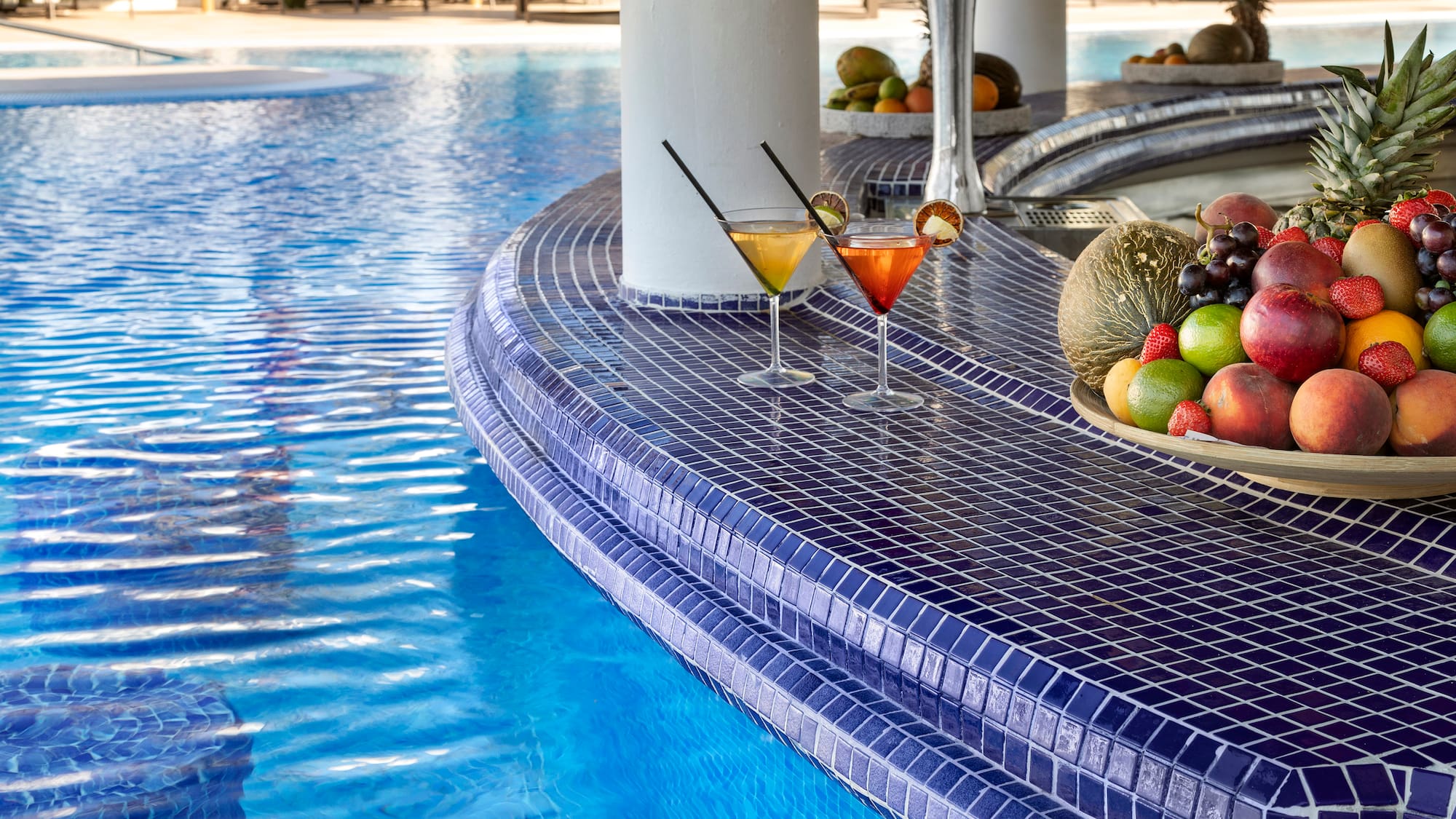 a pool with a bowl of fruit and a plate of fruit on the side