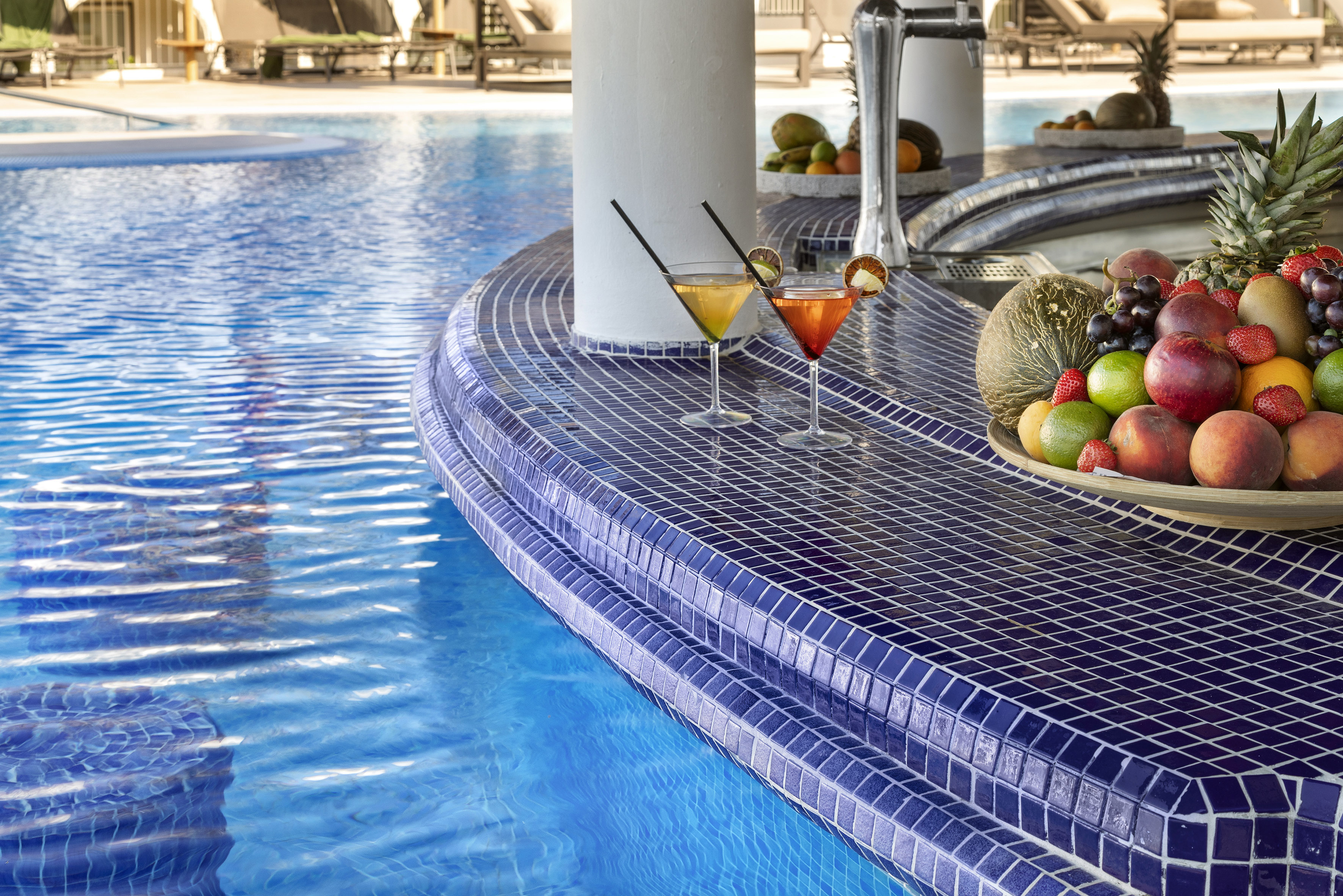 a pool with a bowl of fruit and a plate of fruit on the side