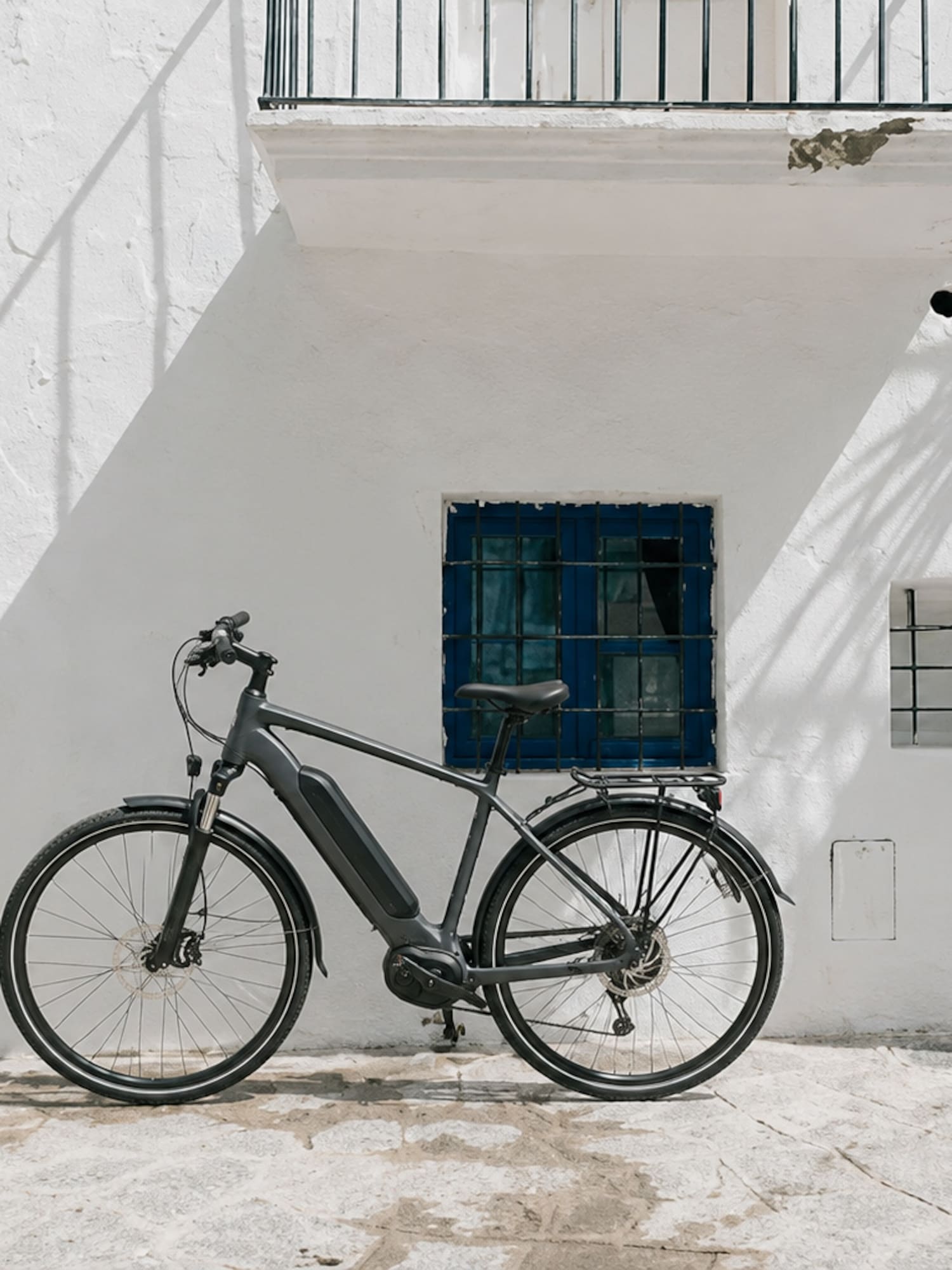 Modern e-bike parked against a white Mediterranean building with blue door.