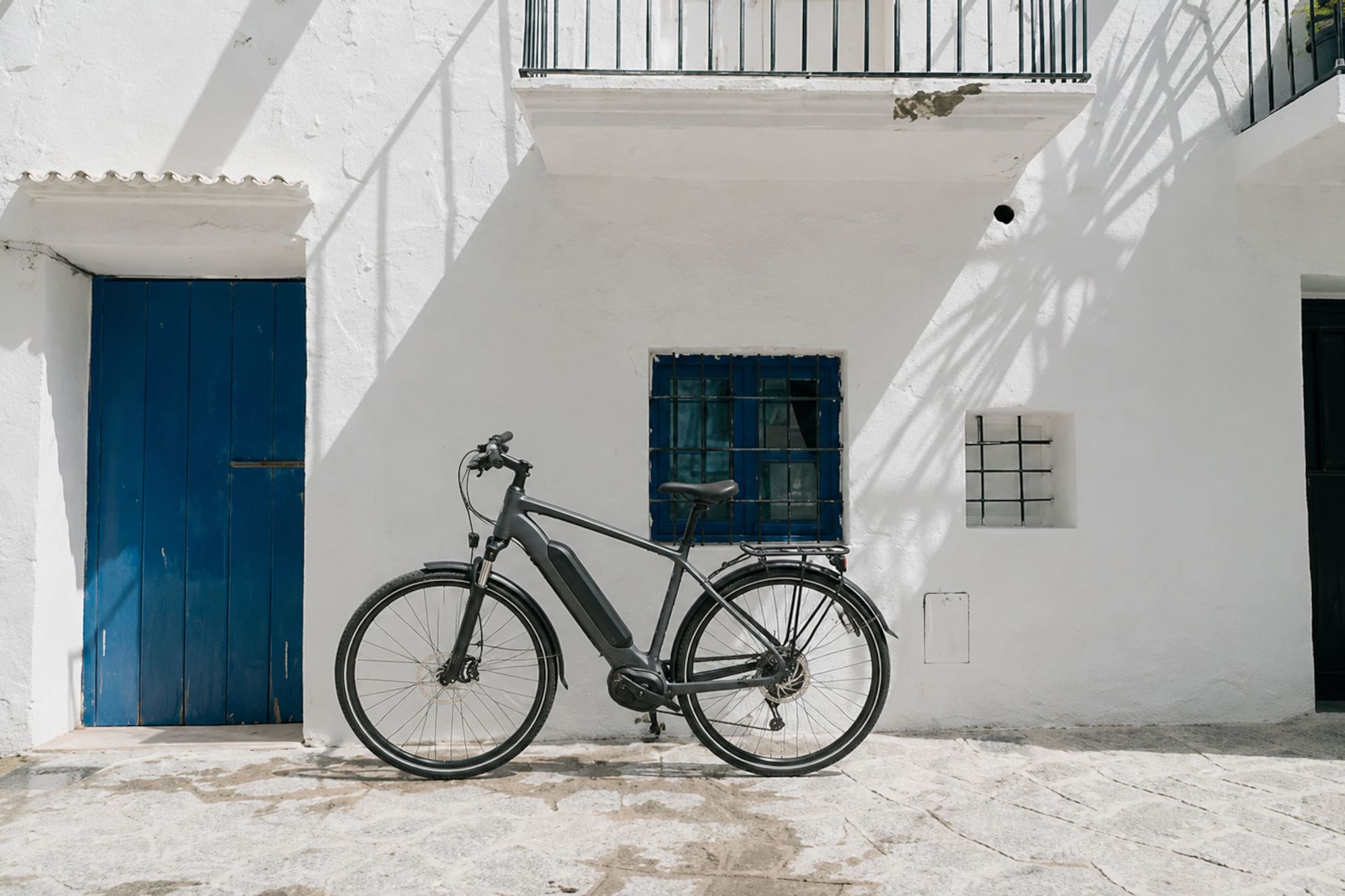 Modern e-bike parked against a white Mediterranean building with blue door.
