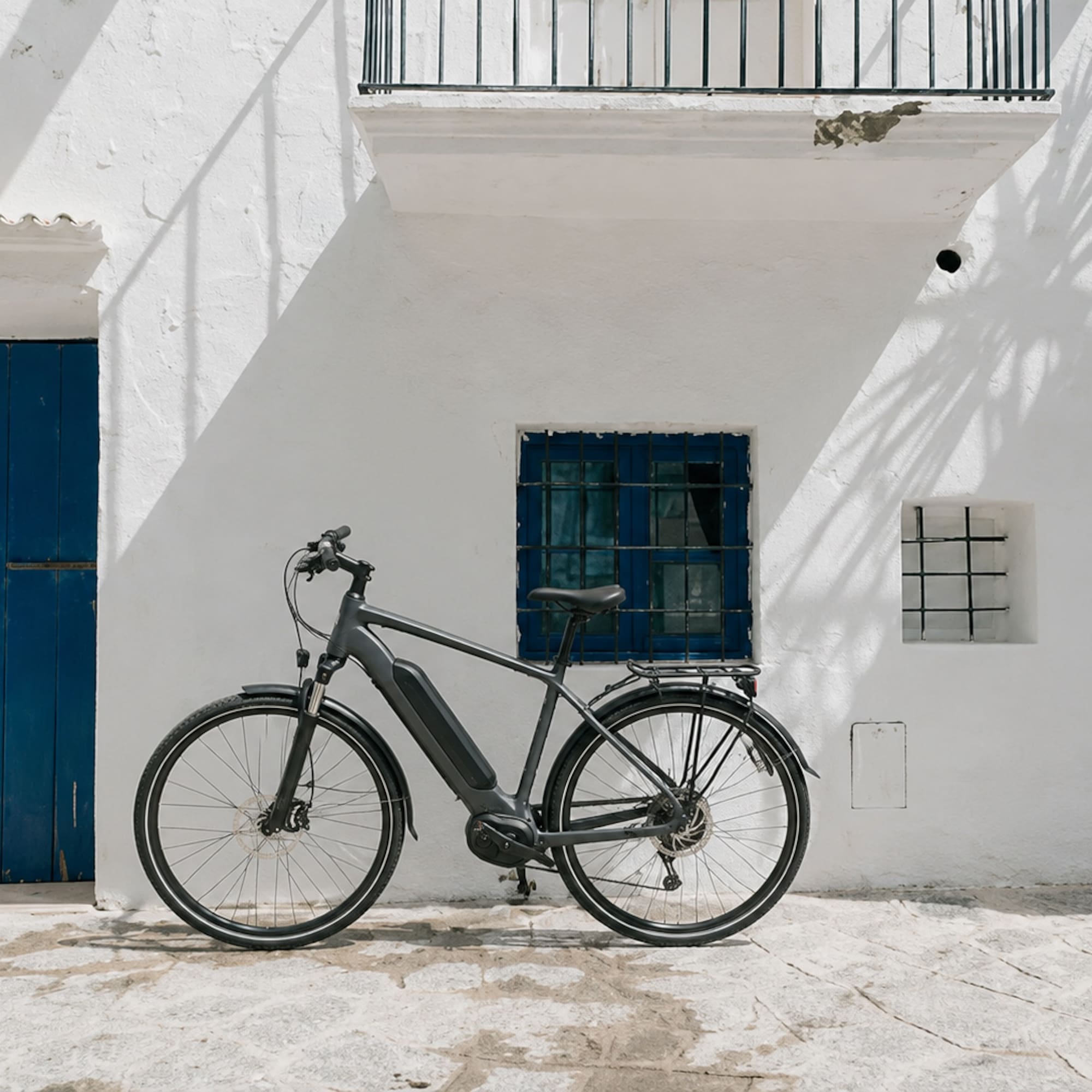 Modern e-bike parked against a white Mediterranean building with blue door.