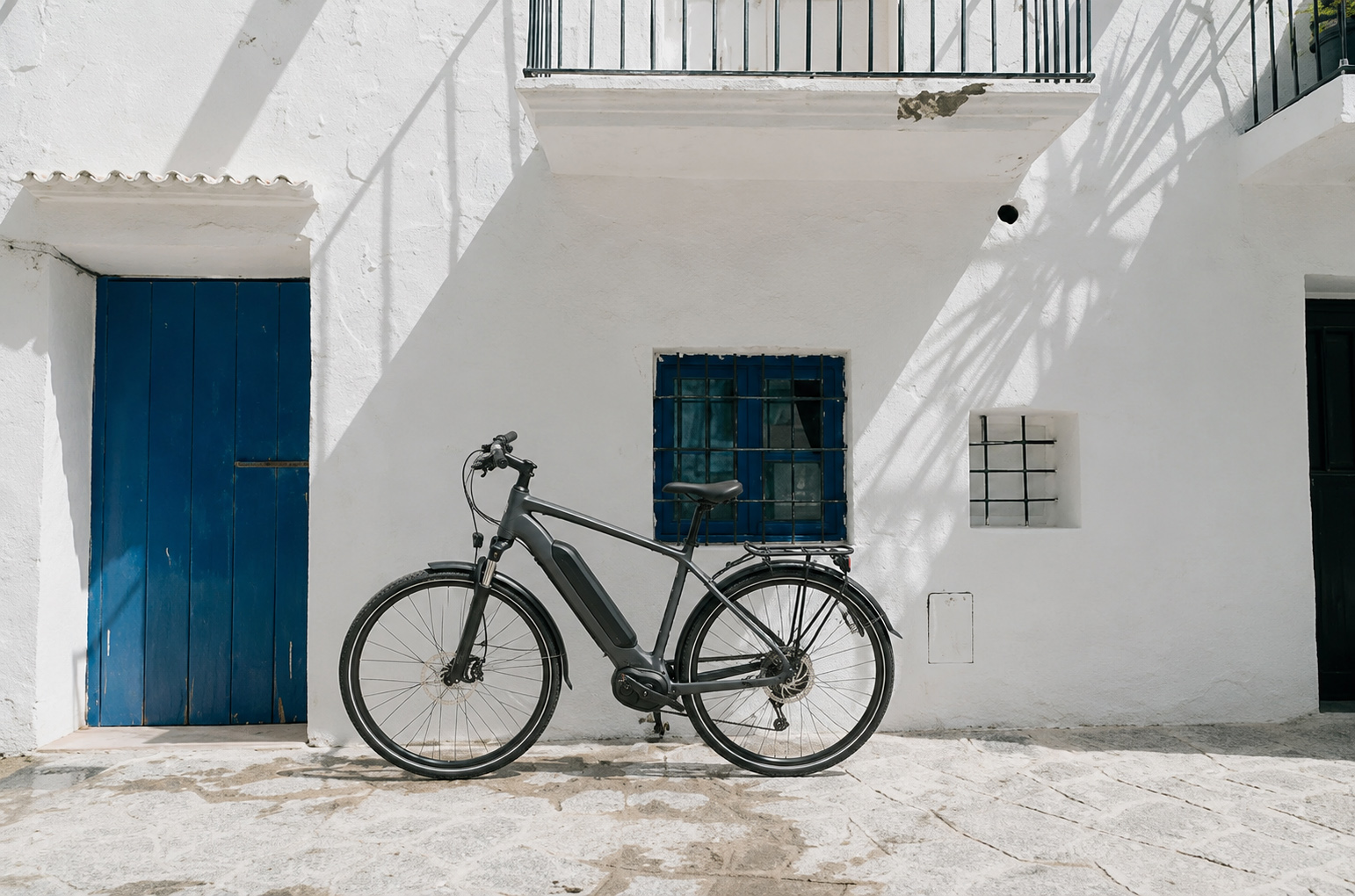 Modern e-bike parked against a white Mediterranean building with blue door.