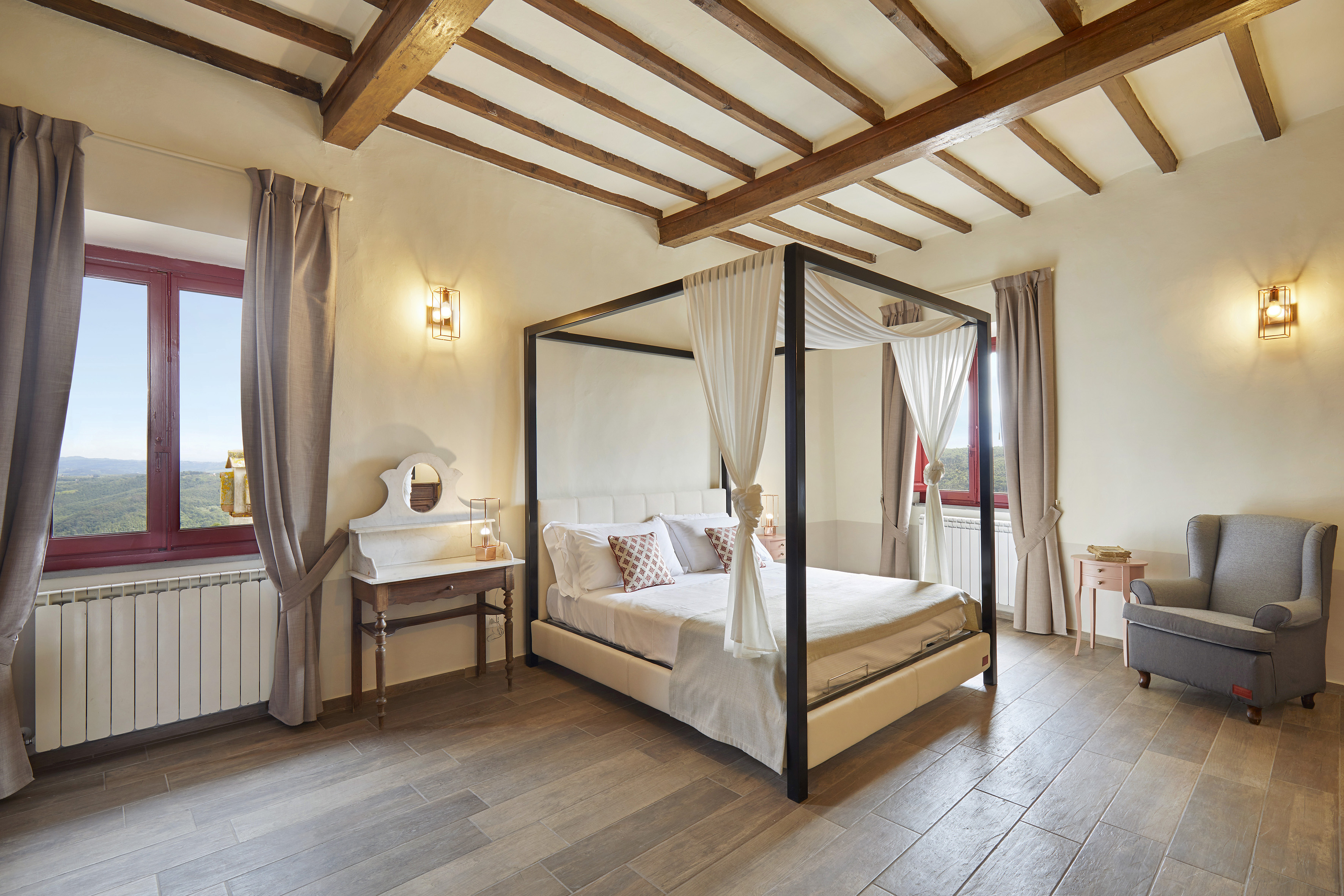 Bedroom with four-poster bed, rustic wooden beams, and countryside window view.