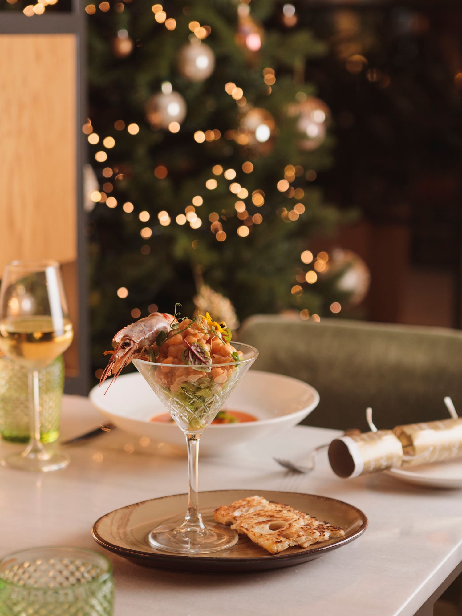 Shrimp cocktail in martini glass, wine, crackers, festive Christmas dinner table.