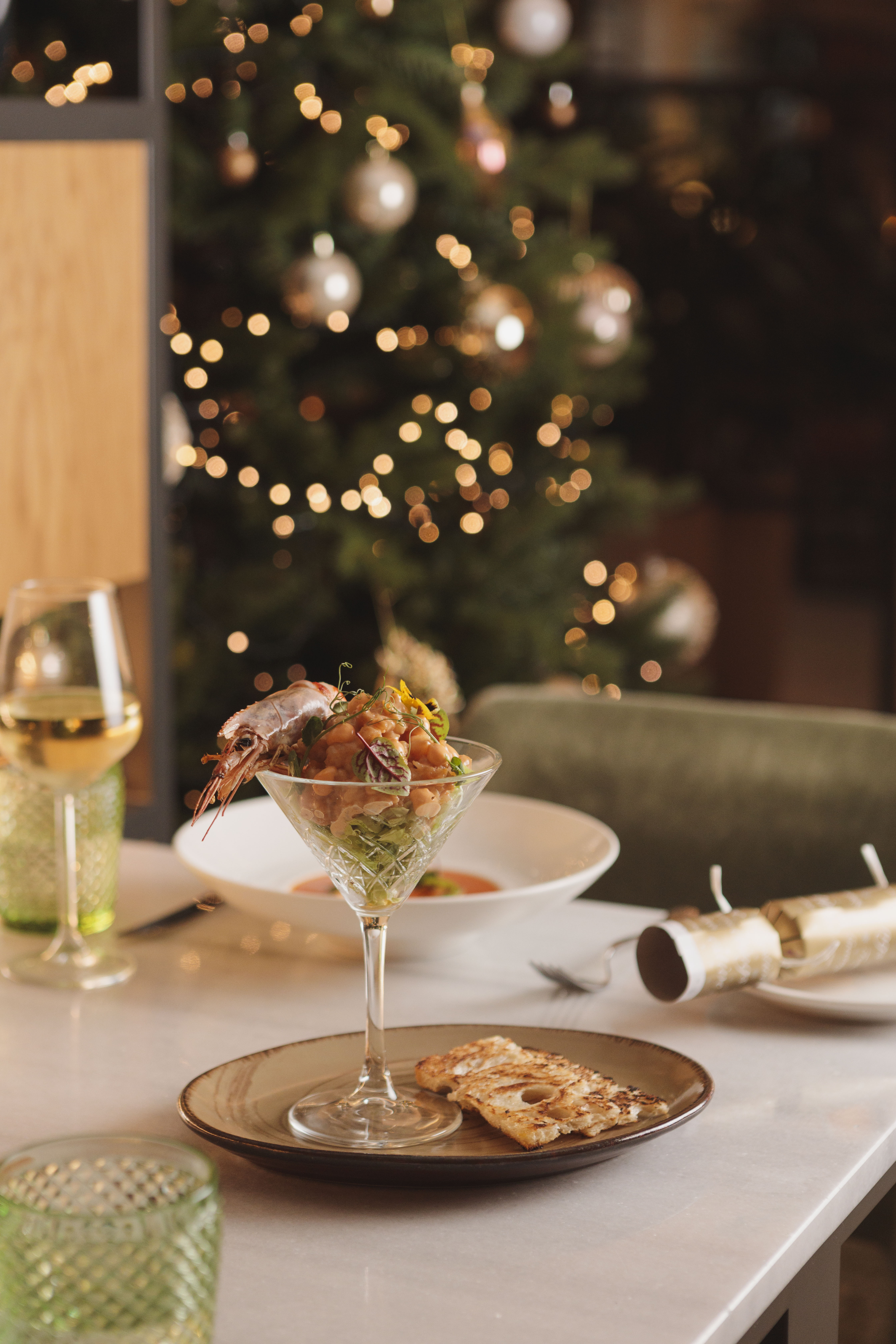 Shrimp cocktail in martini glass, wine, crackers, festive Christmas dinner table.