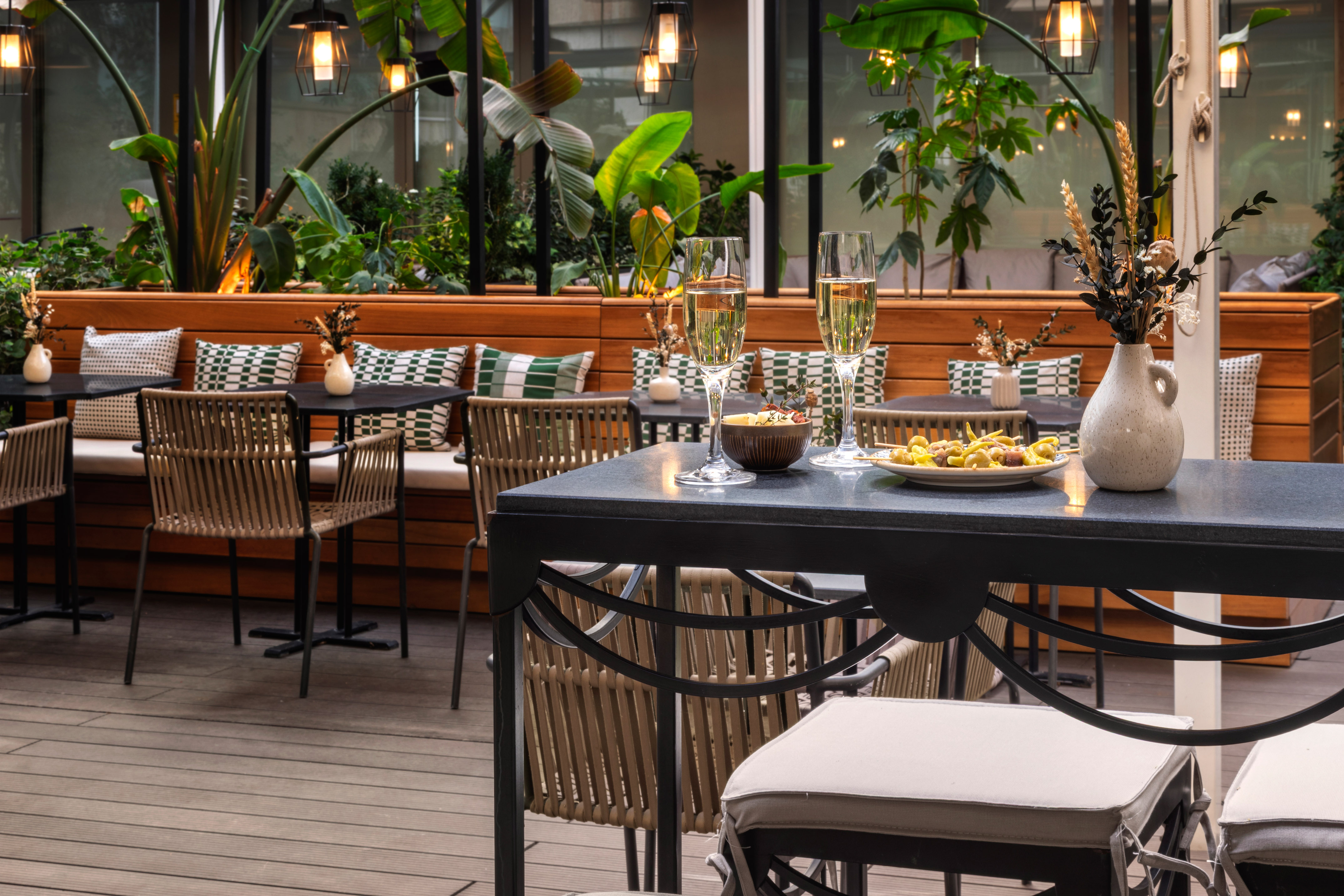 Stylish outdoor restaurant patio with champagne, appetizers, and lush greenery.