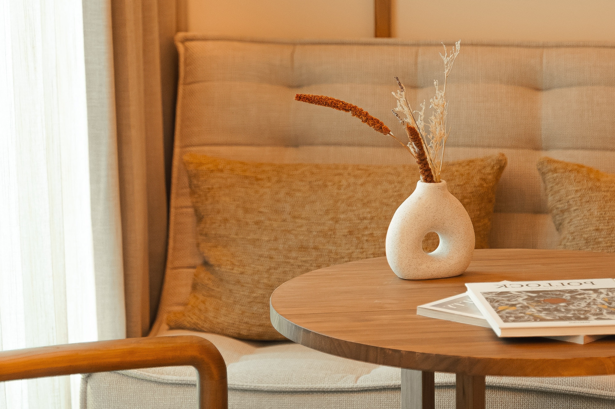 a table with a vase of dry flowers on it