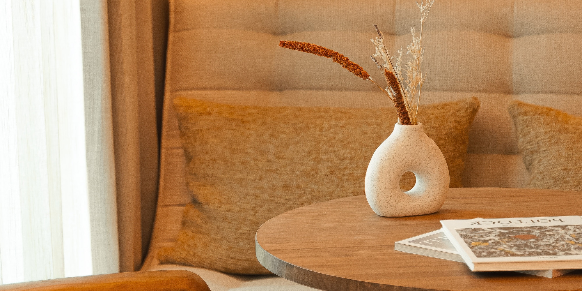 a table with a vase of dry flowers on it