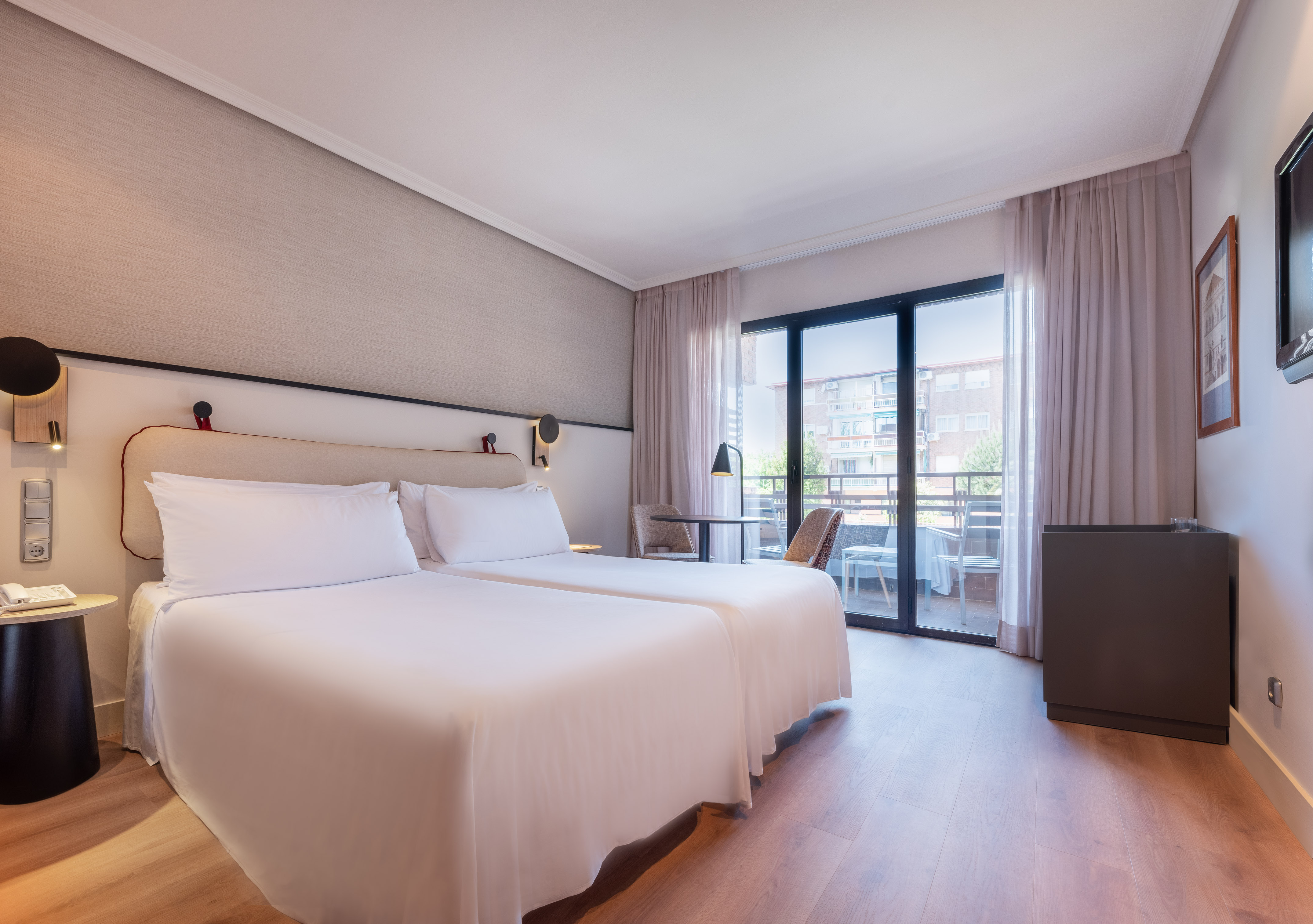 Bright hotel room with twin beds, modern decor, and balcony.