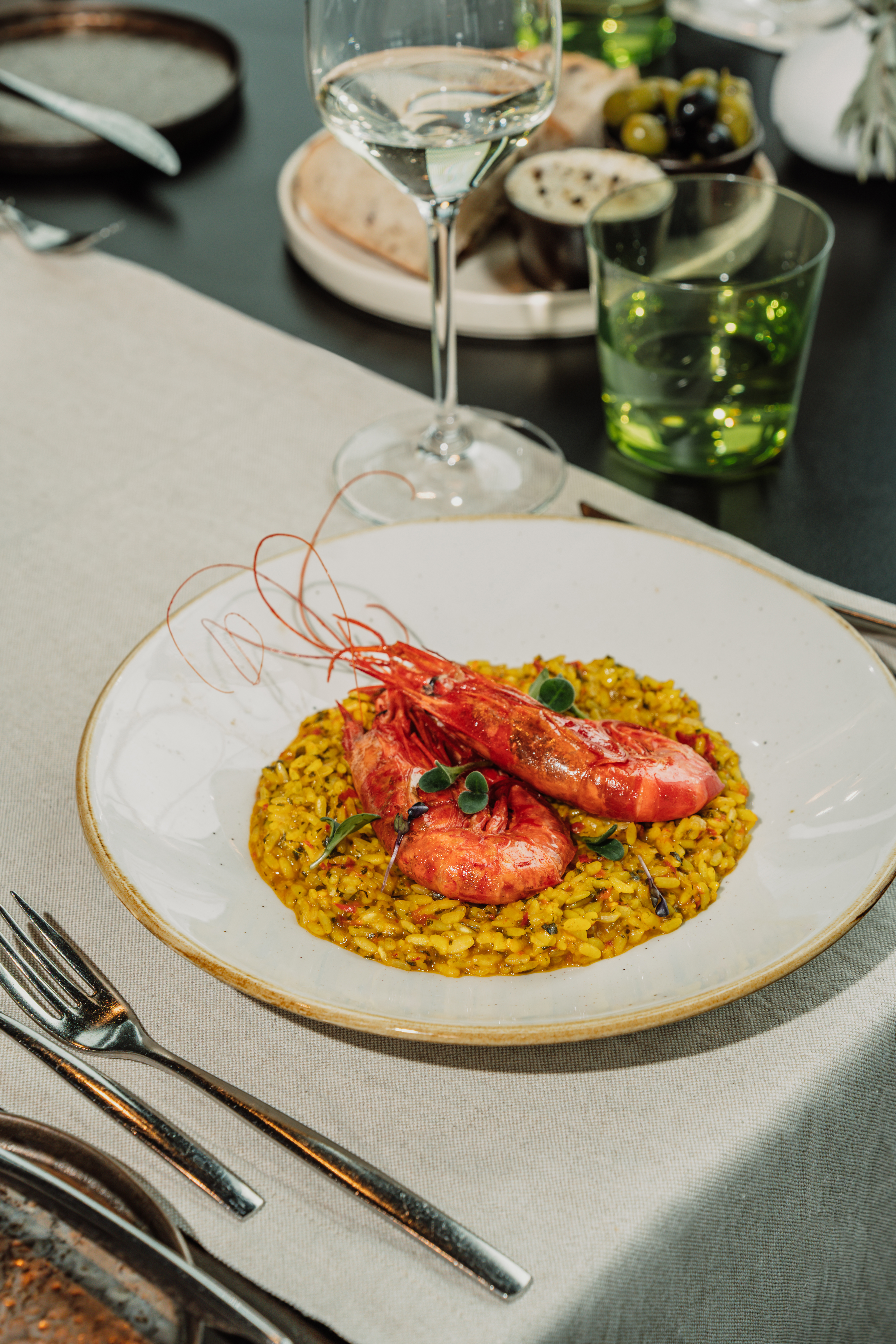 Gourmet red prawns with yellow risotto and herbs, served on a dinner plate.