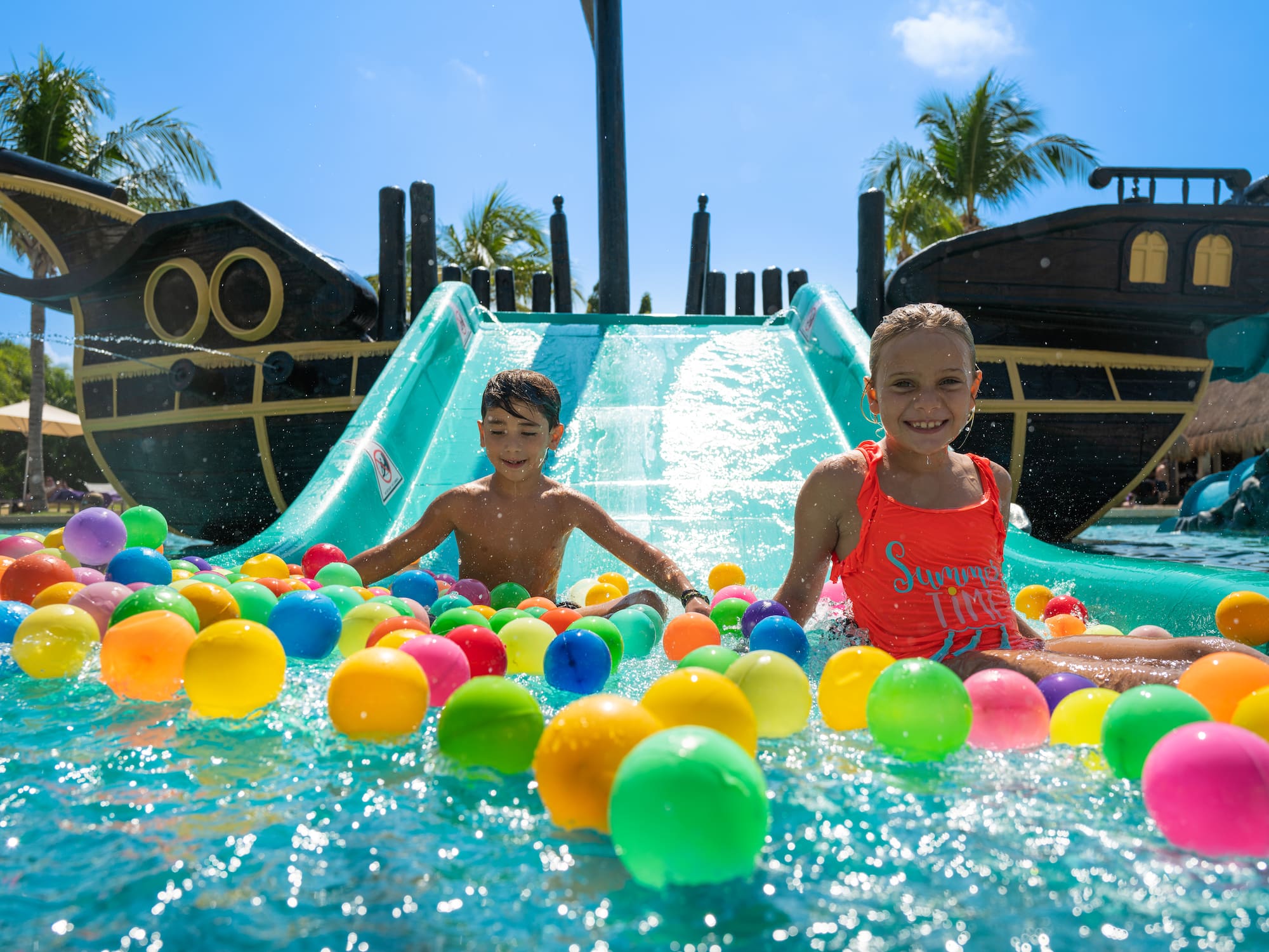 a boy and girl in a water slide with balls