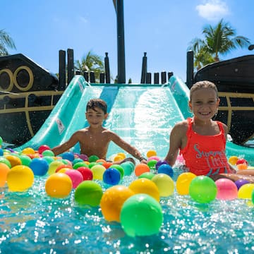 a boy and girl in a water slide with balls