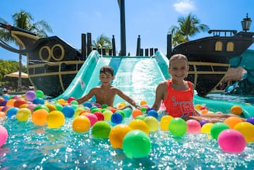 a boy and girl in a water slide with balls