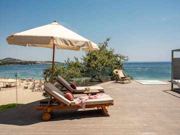 a deck with chairs and umbrella on a beach