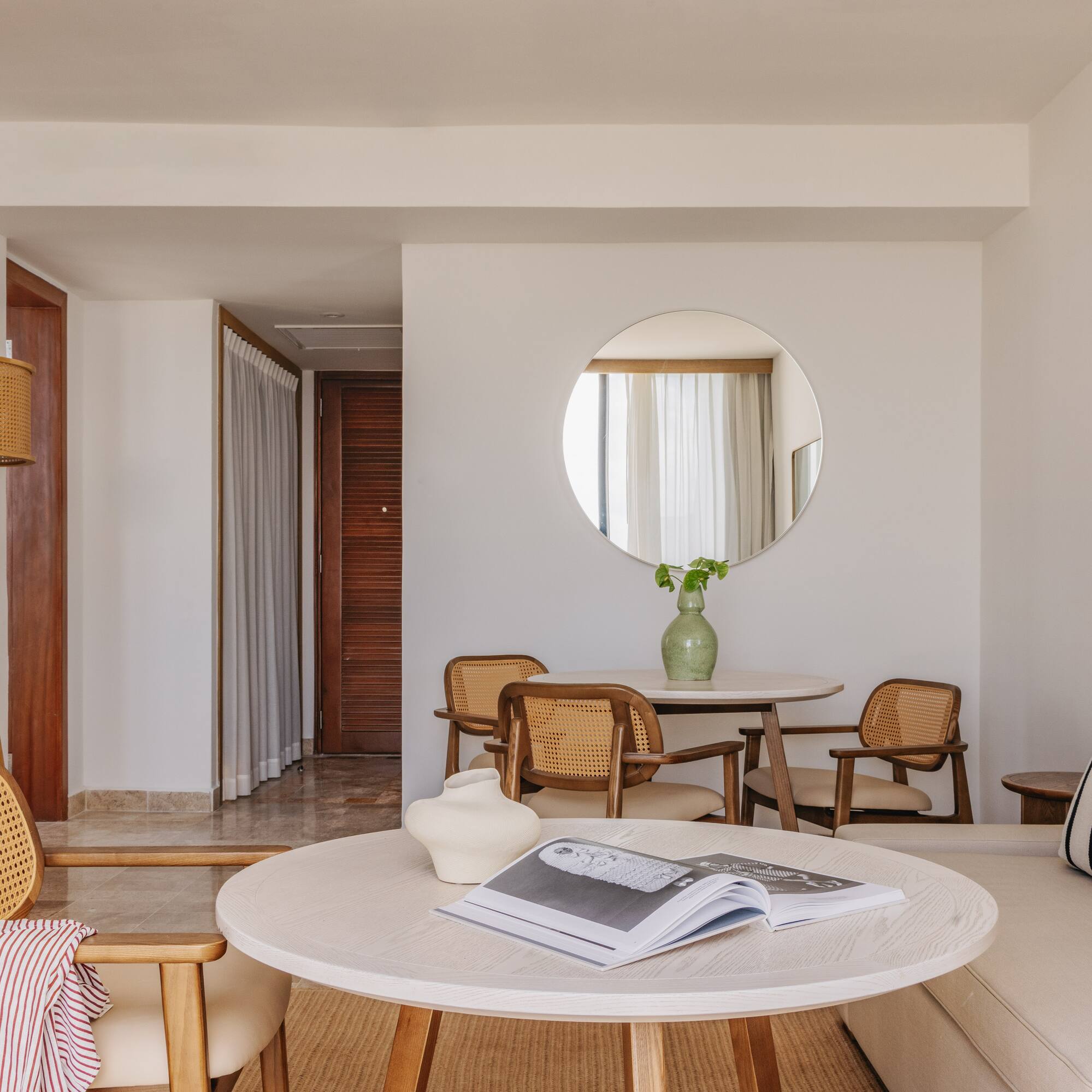 Resort suite living room with light wood and cane furniture, sofa, round tables.