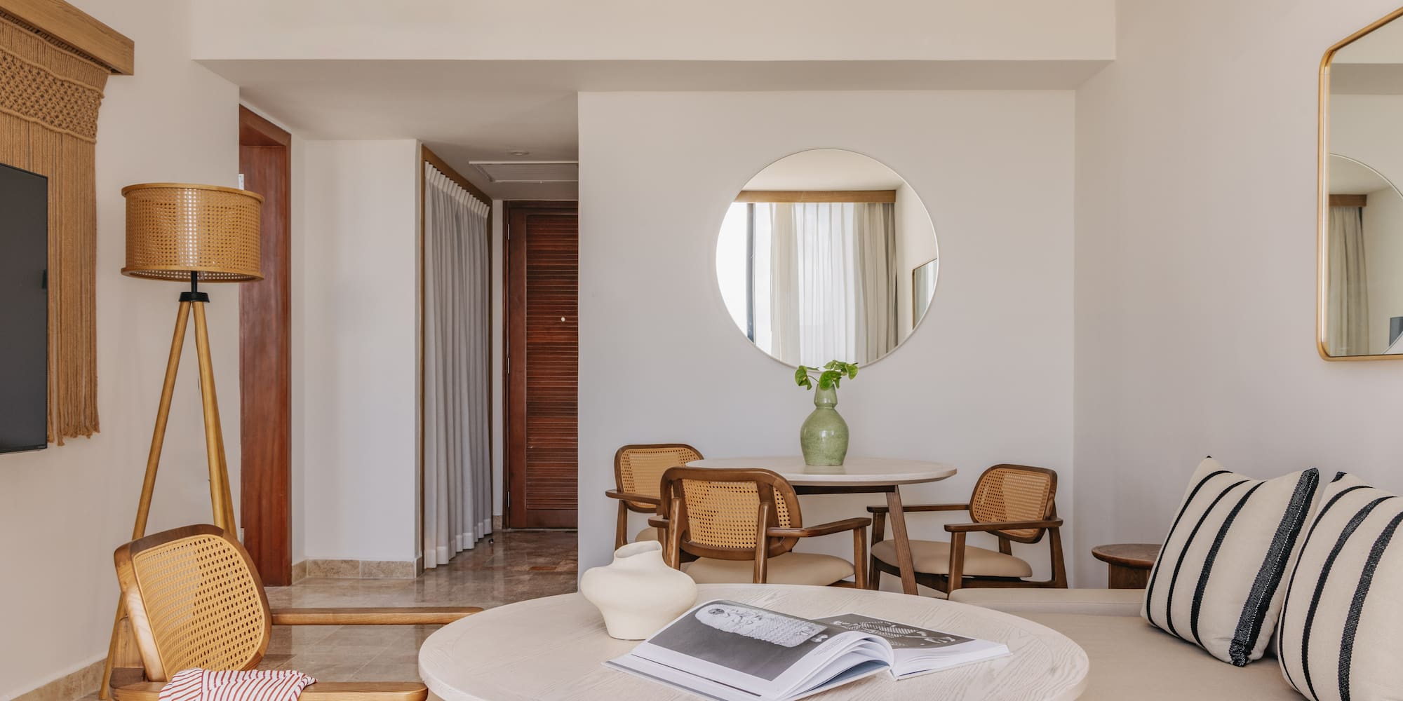 Resort suite living room with light wood and cane furniture, sofa, round tables.